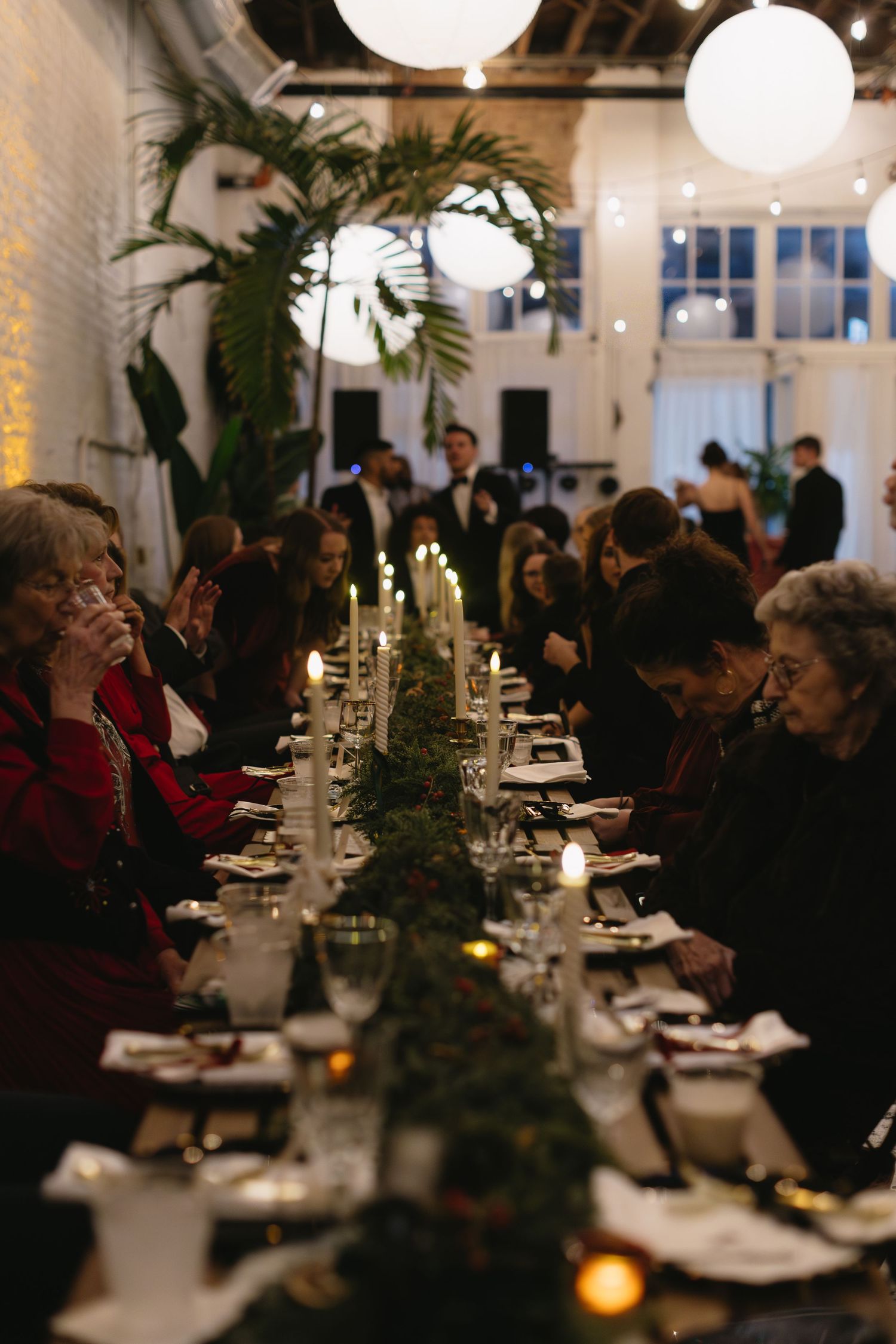 An elegant wedding reception dinner table with candlelight and greenery decorations.