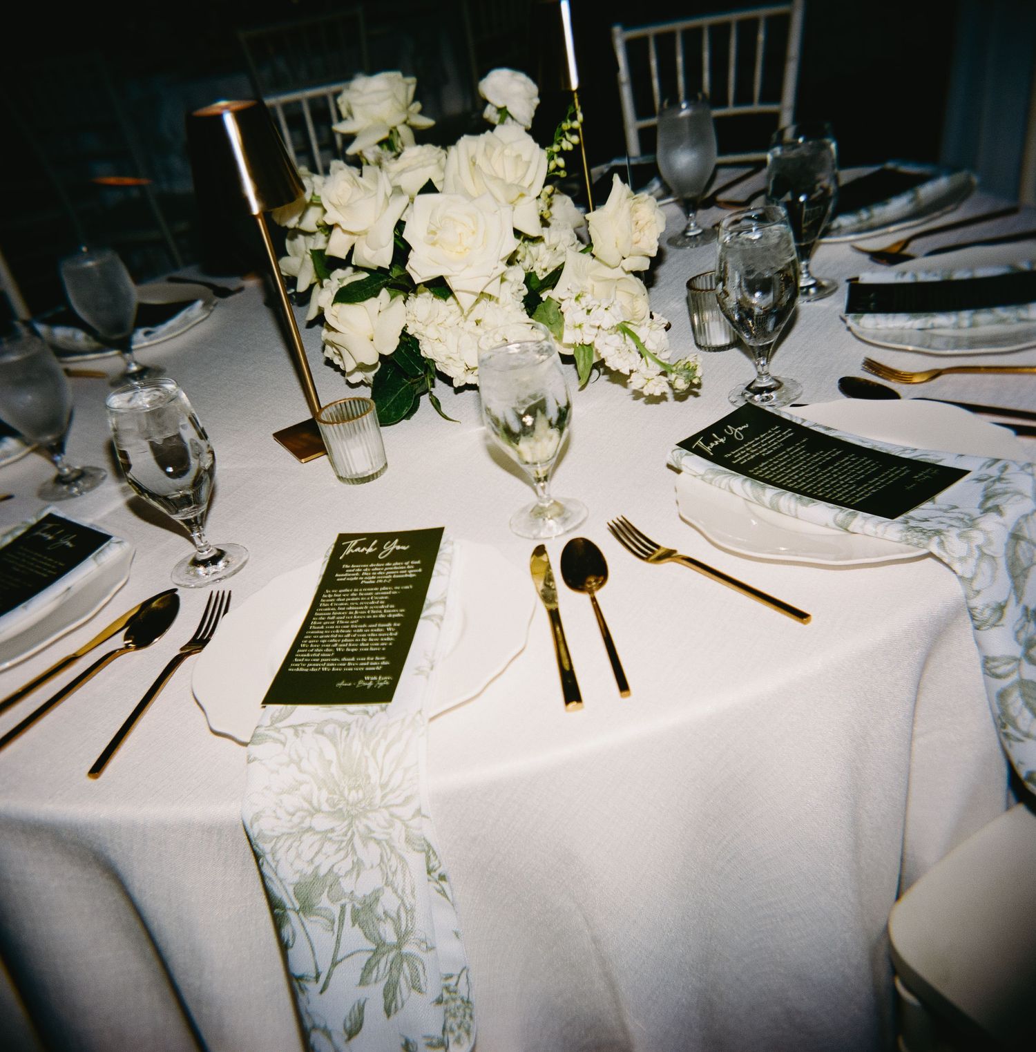 Wedding reception table settings with white linens and floral arrangements captured in black and white.