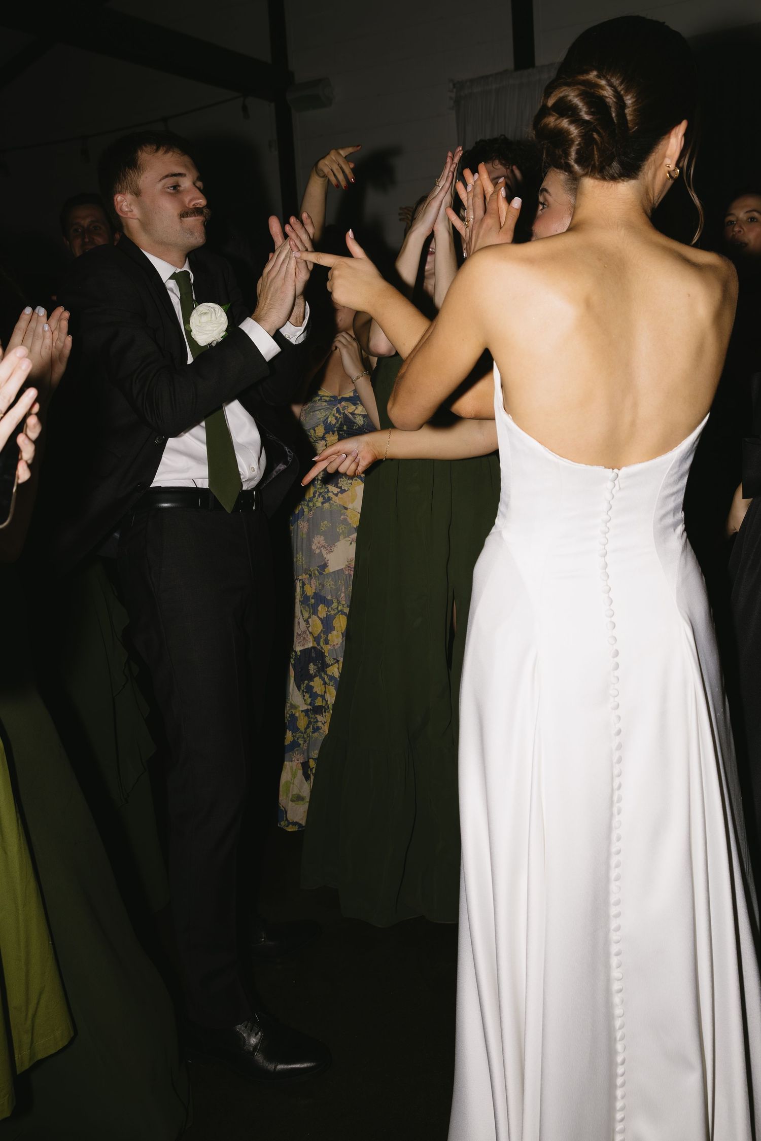 Wedding guests dancing and celebrating at an indoor reception.