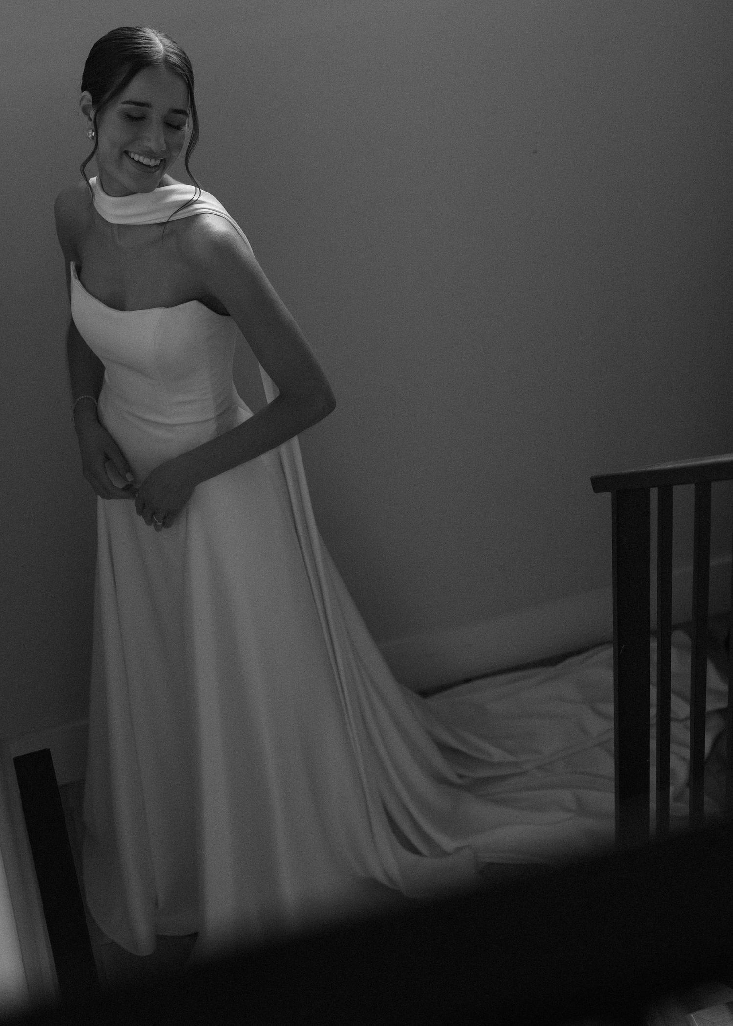 A bride in an elegant white strapless gown poses in dramatic lighting.