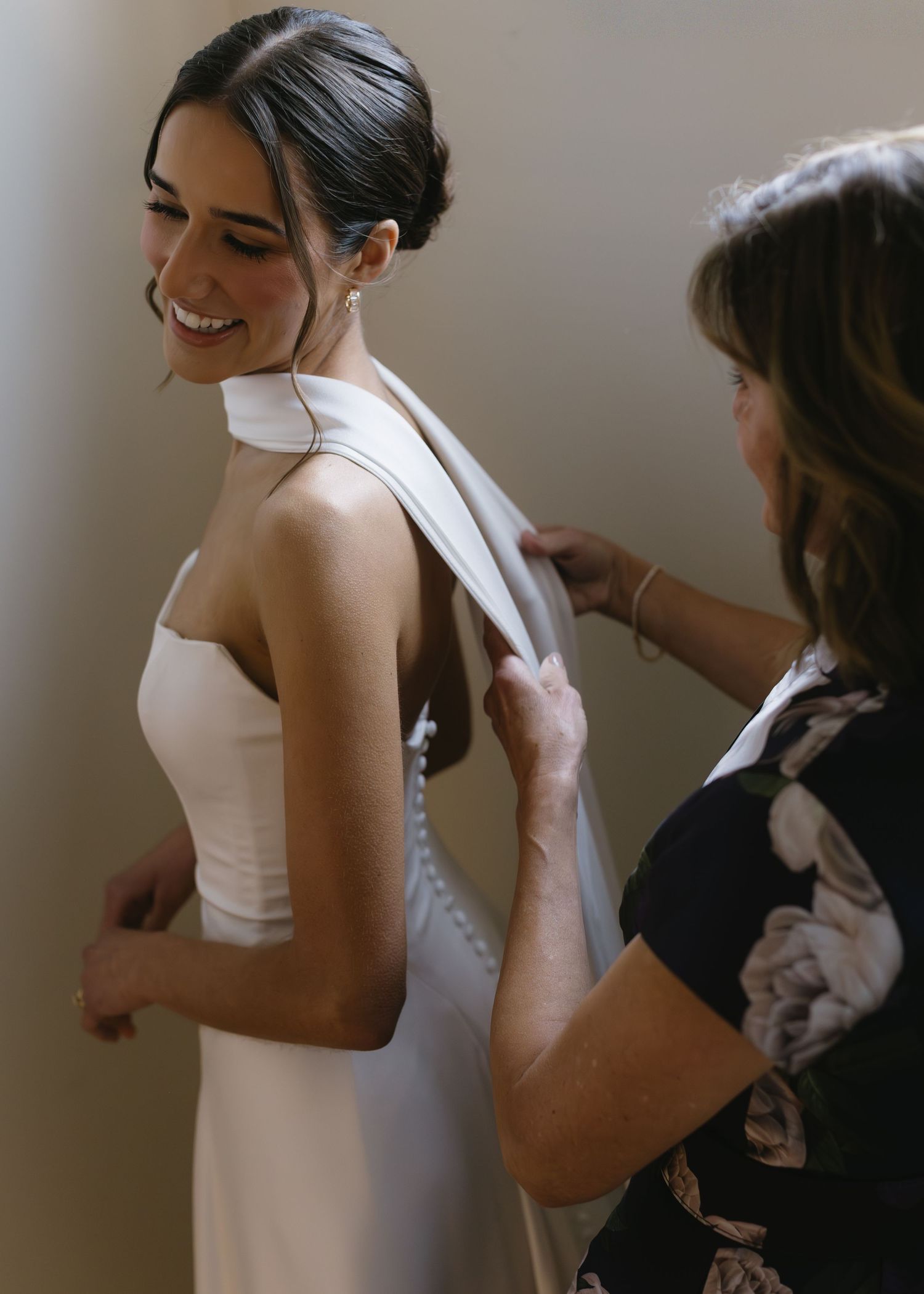 Behind-the-scenes shots of a bride getting dressed with help from others.