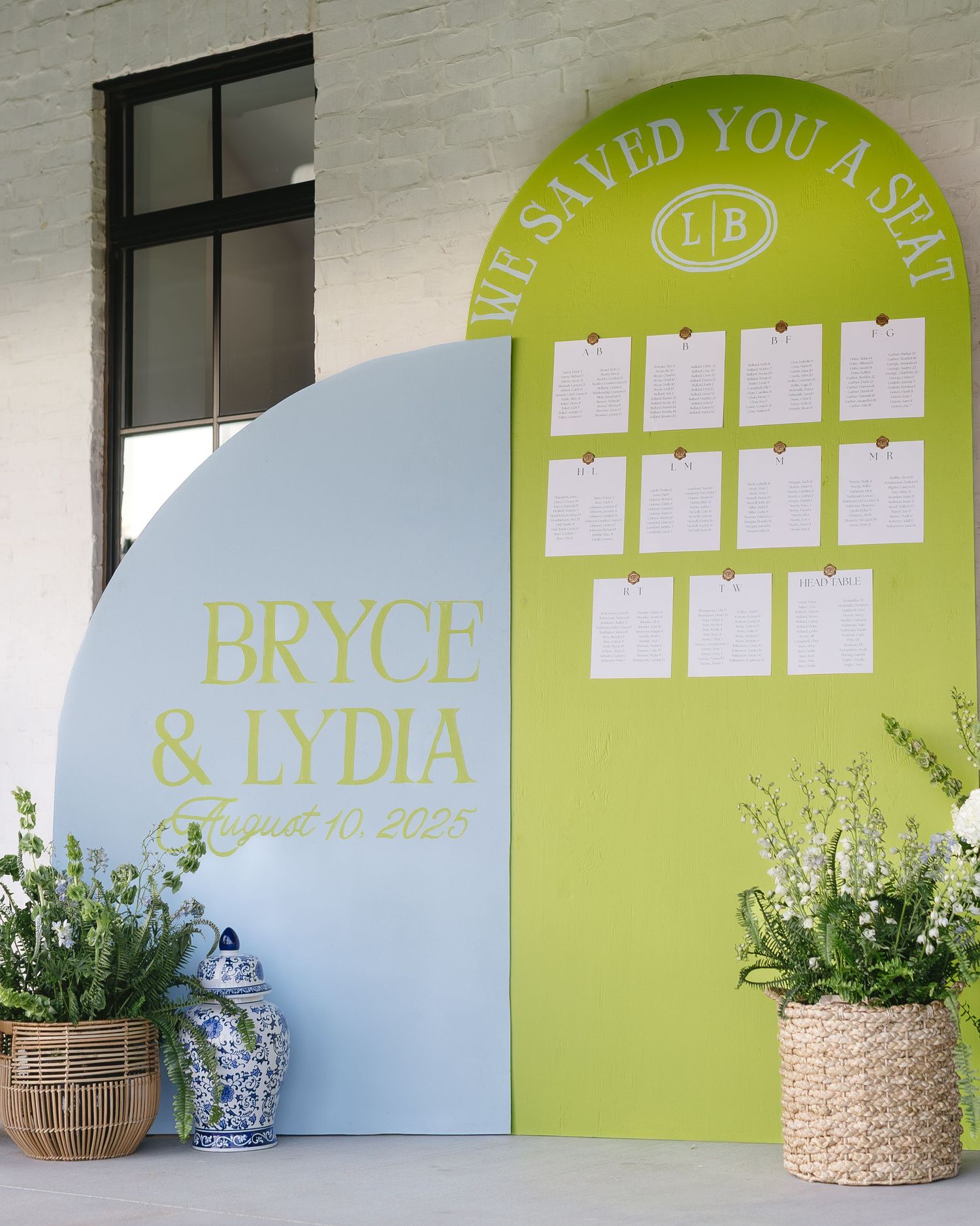 Wedding reception seating chart with lime green and blue accents displayed on white wall with woven basket decorations.