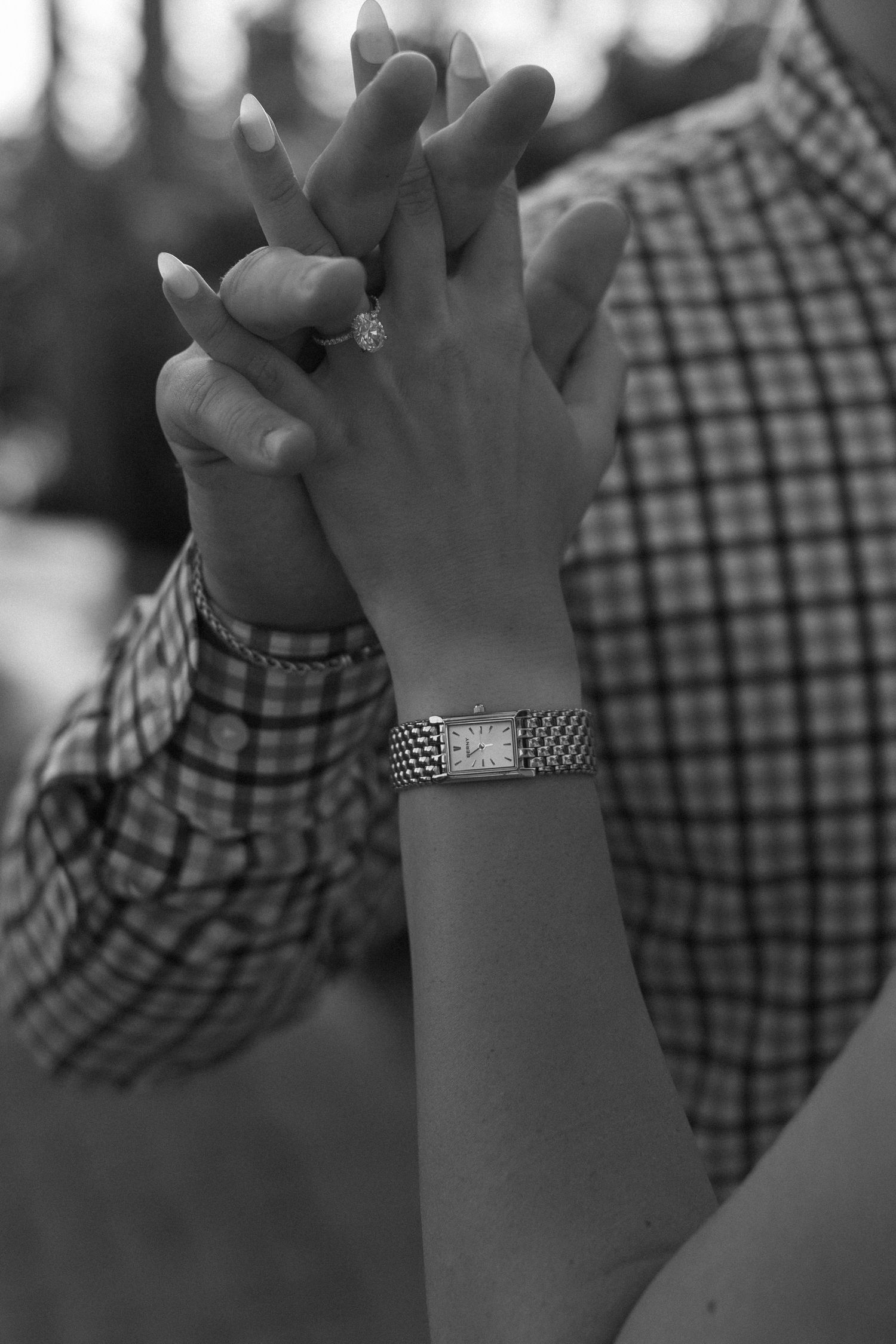 Black and white close-up of hands with watch clasped together in romantic gesture.