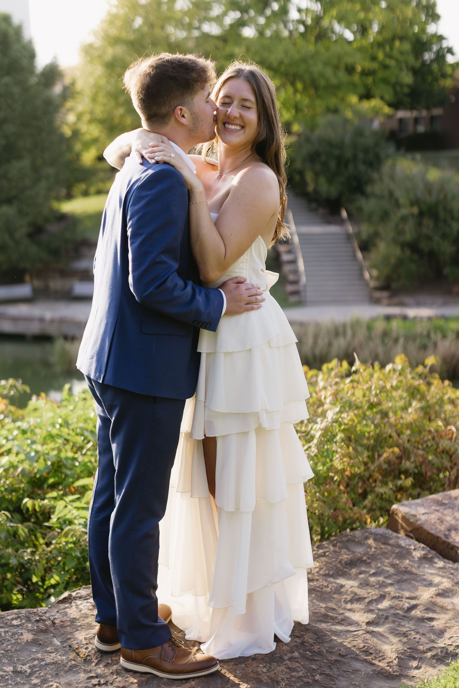 A couple sharing tender moments in a garden setting during sunset.