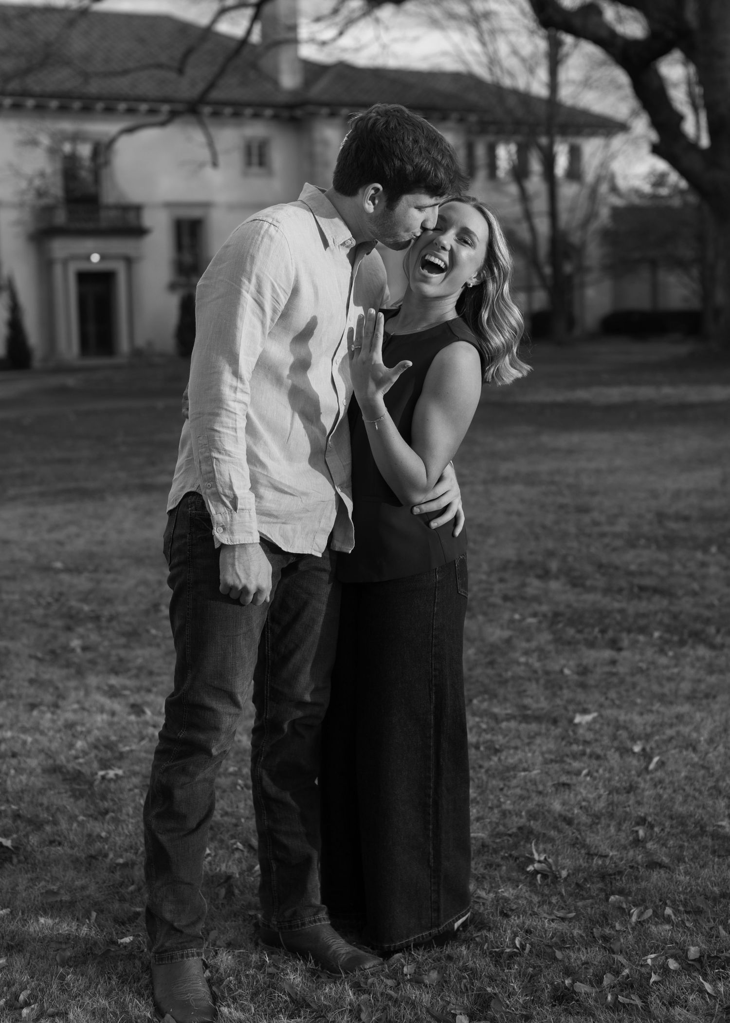 A black and white photo of a couple sharing tender moments outdoors.
