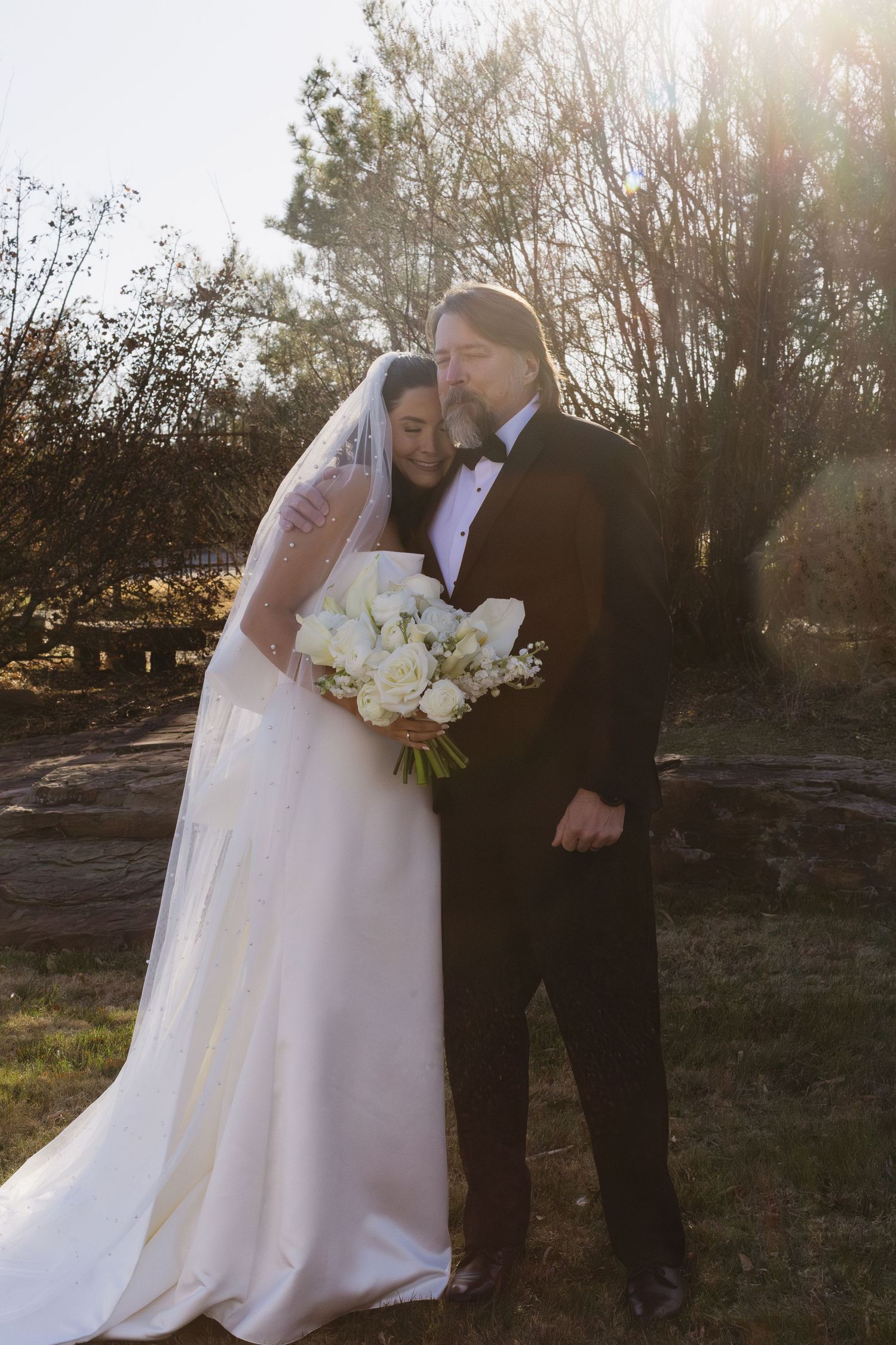 Wedding couple embracing during sunset photo session in natural outdoor setting.