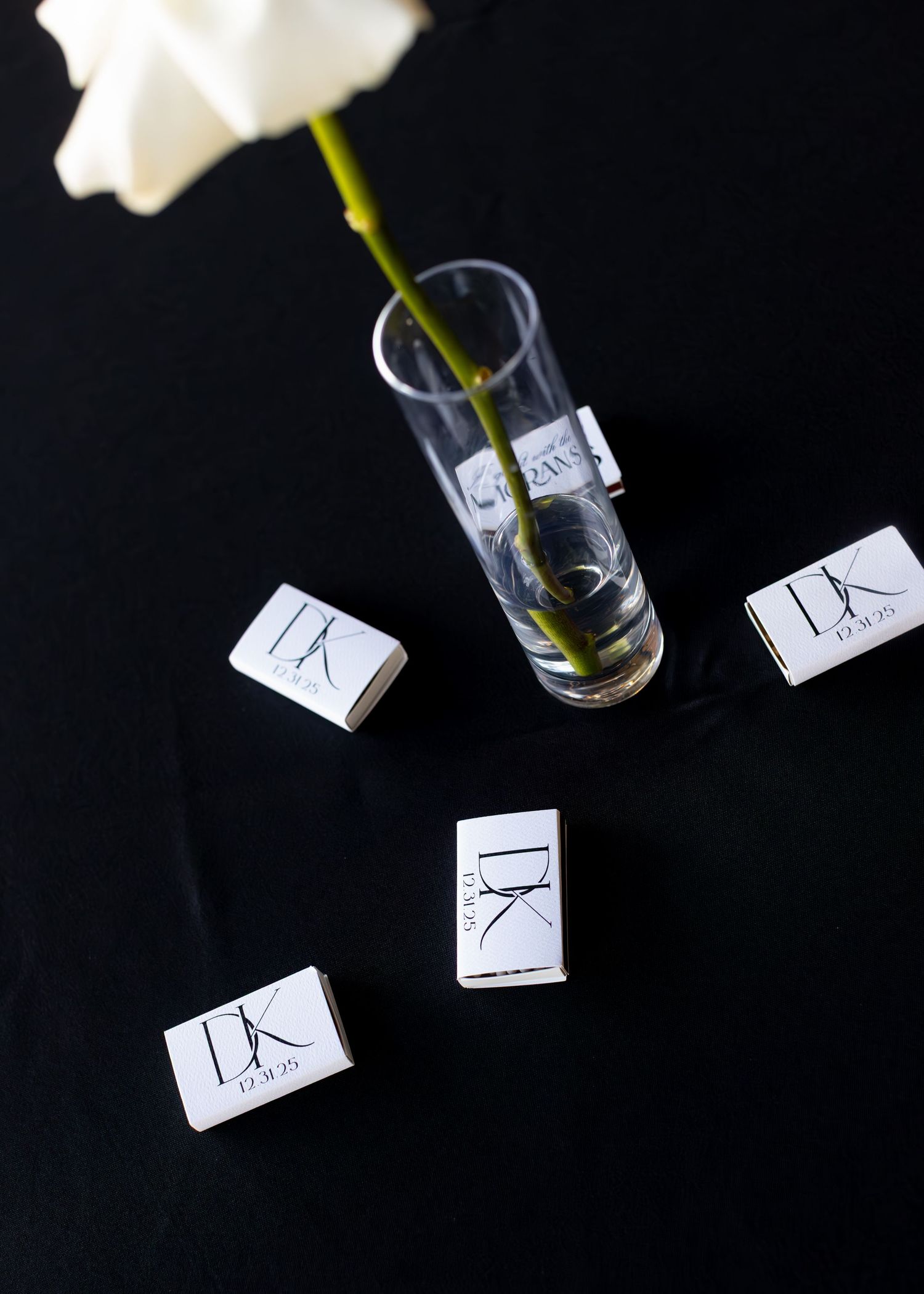 Small paper place cards scattered around wine glasses on a black surface.