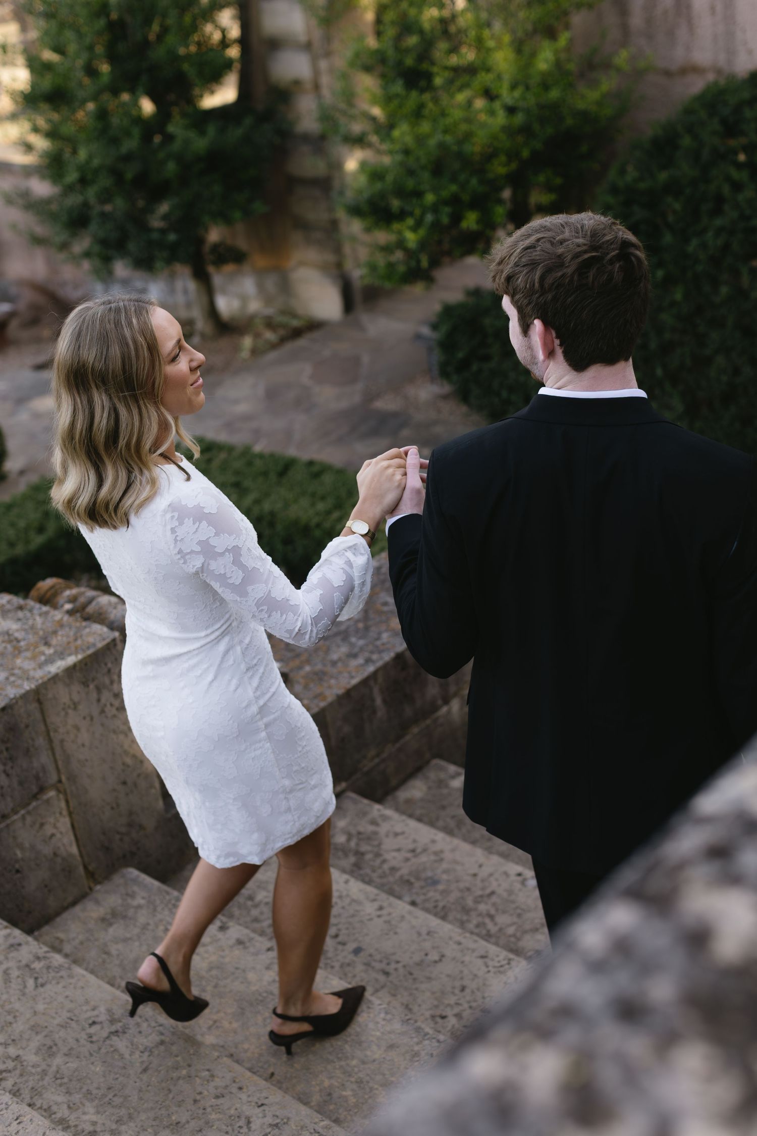 A playful series of wedding photos capturing a couple dancing on stone steps outdoors.