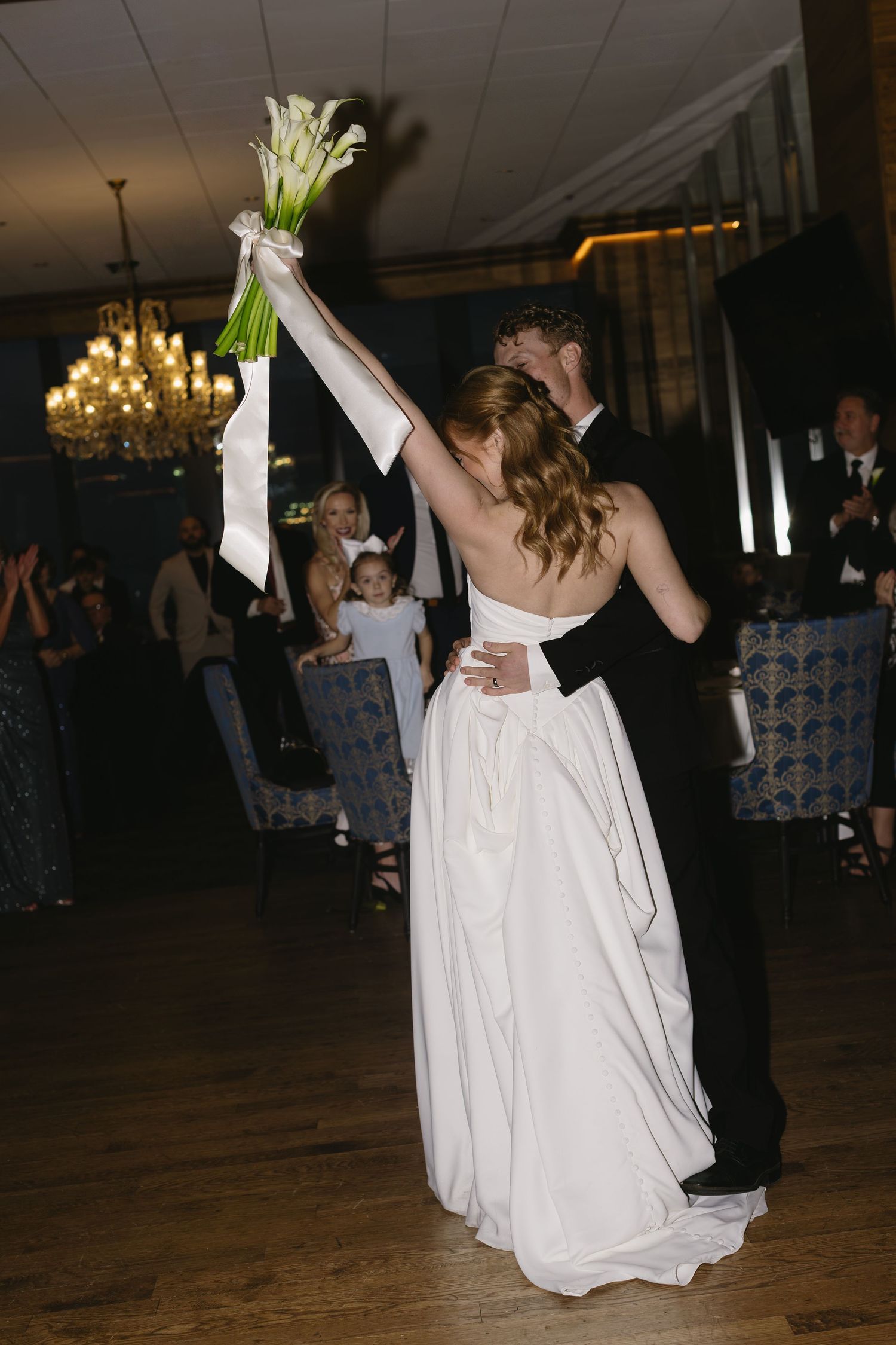 Couple dancing at their wedding reception with the bride in a flowing white gown and groom in black suit.