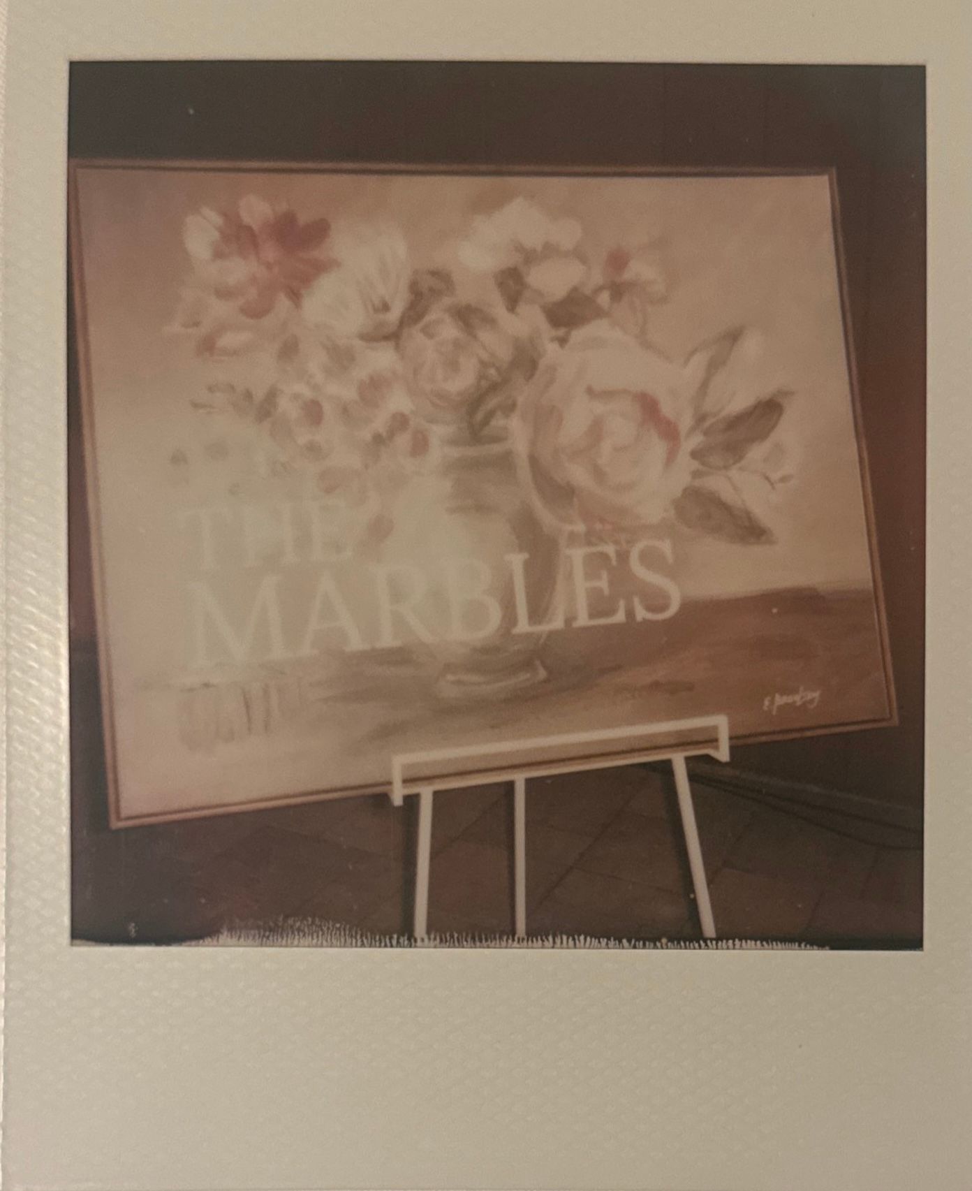 A series of vintage-style art prints displayed on easels showing faded floral designs in muted tones.