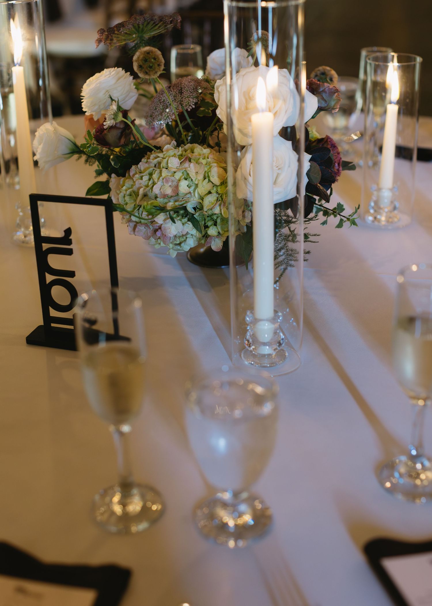 Elegant wedding reception table setting with white linens, candles and floral centerpieces.