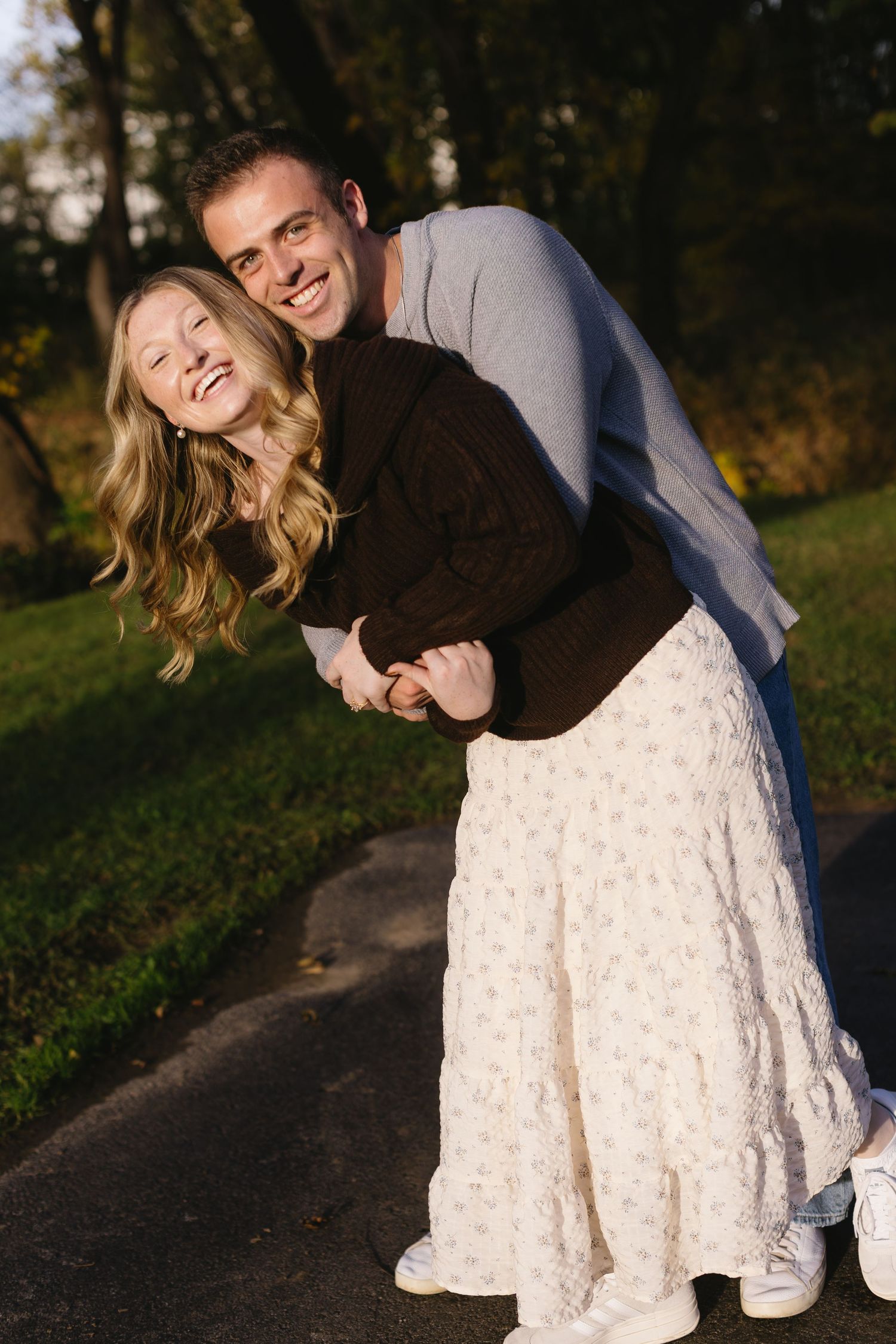 A couple shares a joyful moment together on an autumn path.
