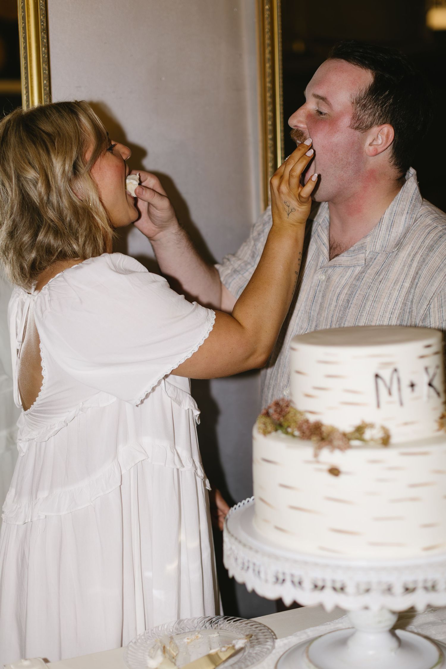 Wedding cake cutting celebration with a white birch-themed cake in the foreground.