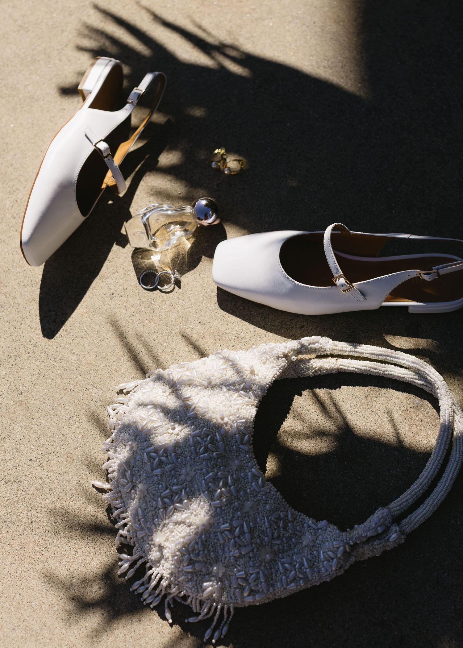 Black and white shoes cast dramatic shadows on a textured beige surface in an artistic composition.