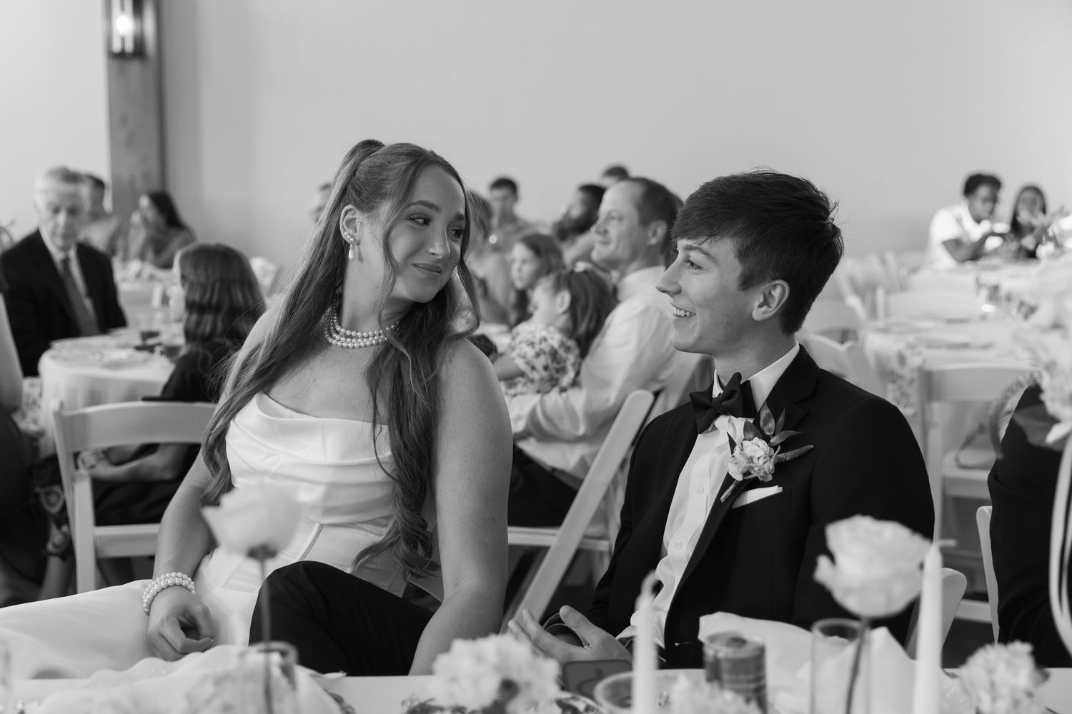 Wedding reception guests seated at tables in a bright indoor venue.