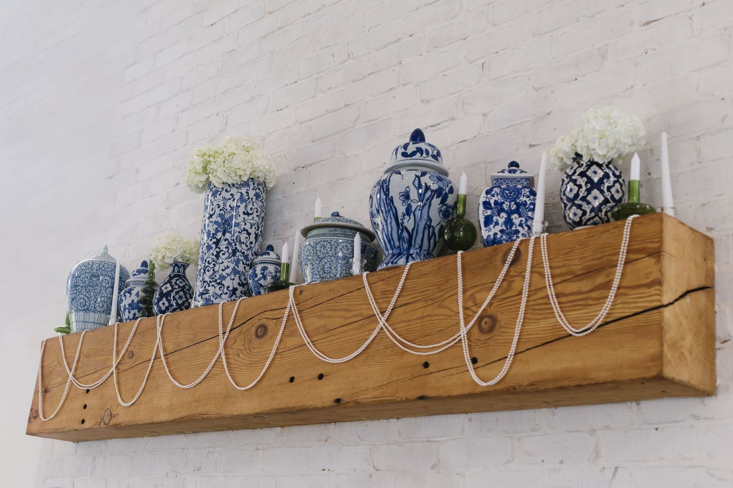 Decorative blue and white chinoiserie vases displayed on wooden floating shelf.