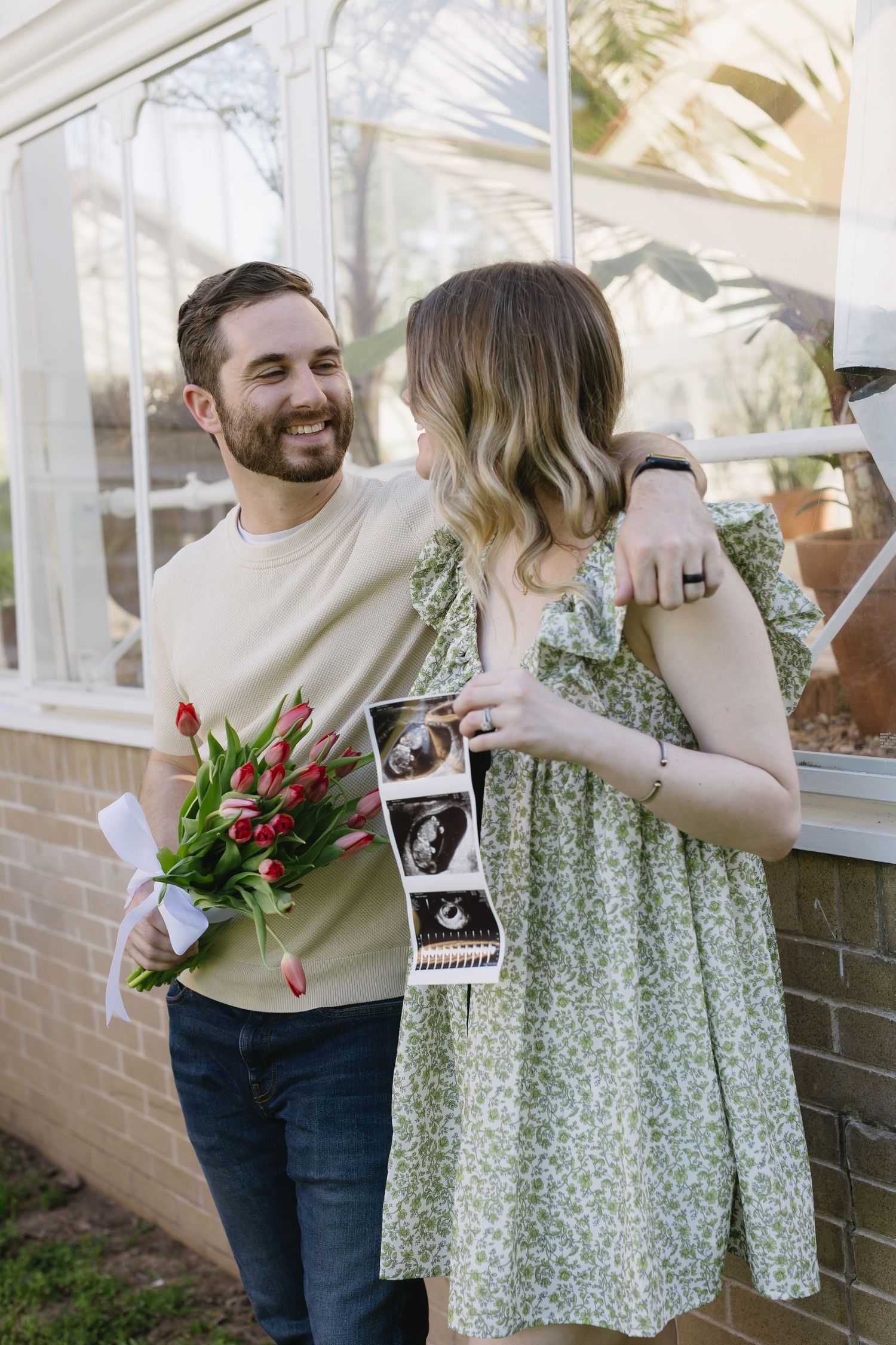 Five connected photos show a couple sharing their pregnancy announcement with tulips and sonogram pictures outdoors.