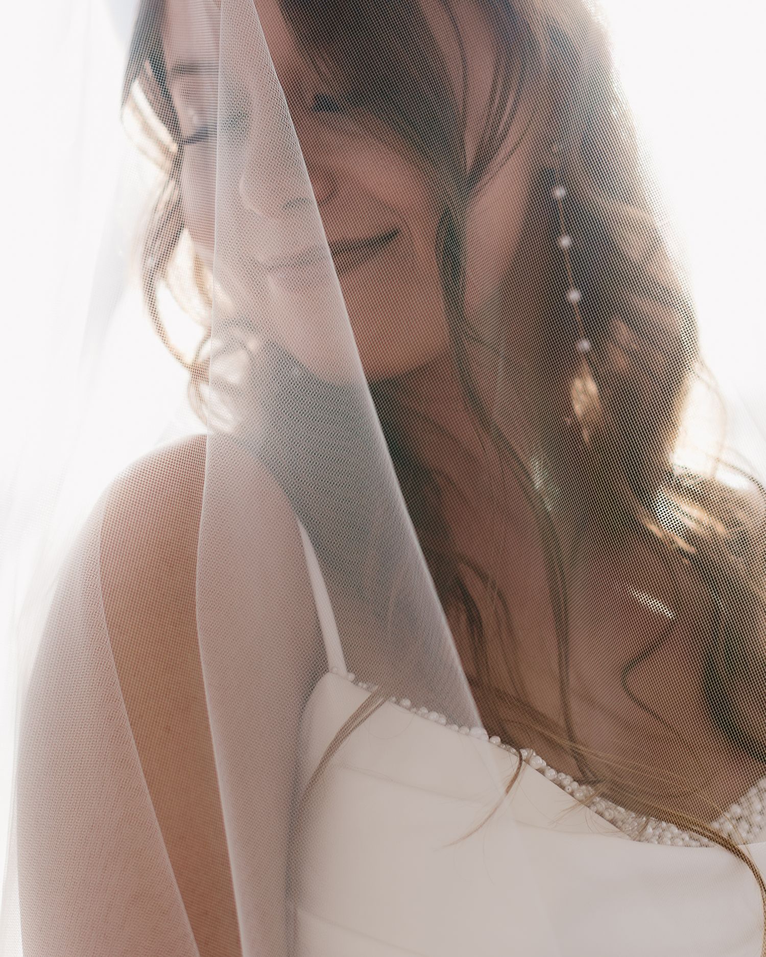 Ethereal bridal portraits captured in soft, dreamy light with a romantic veil creating an artistic effect.