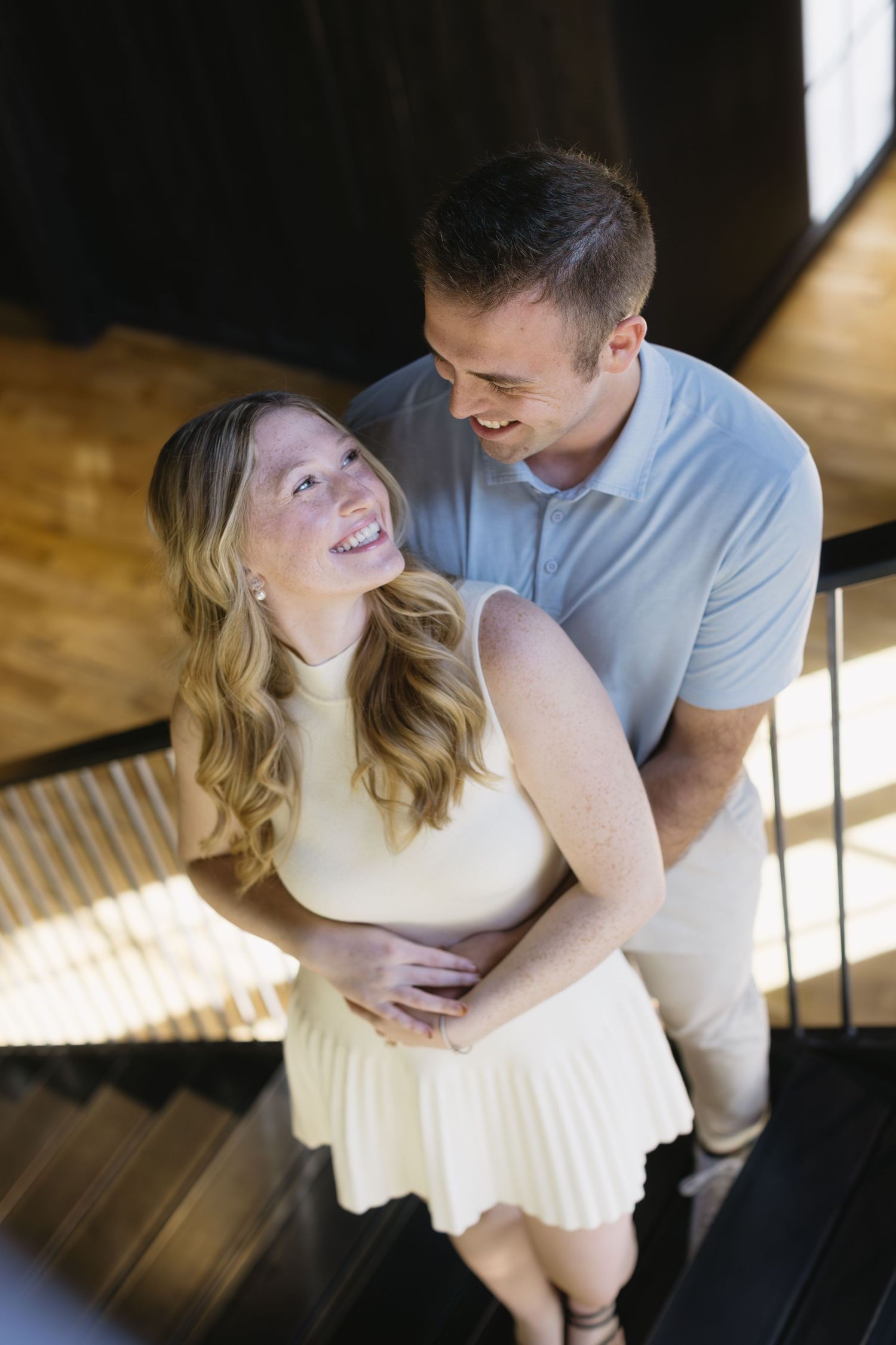A couple shares tender moments during an indoor photoshoot with natural window light.