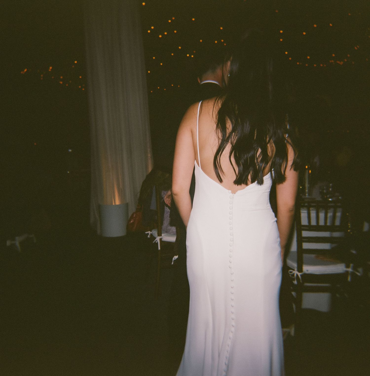 Series of photos showing the back of a white dress against a dark background with string lights.