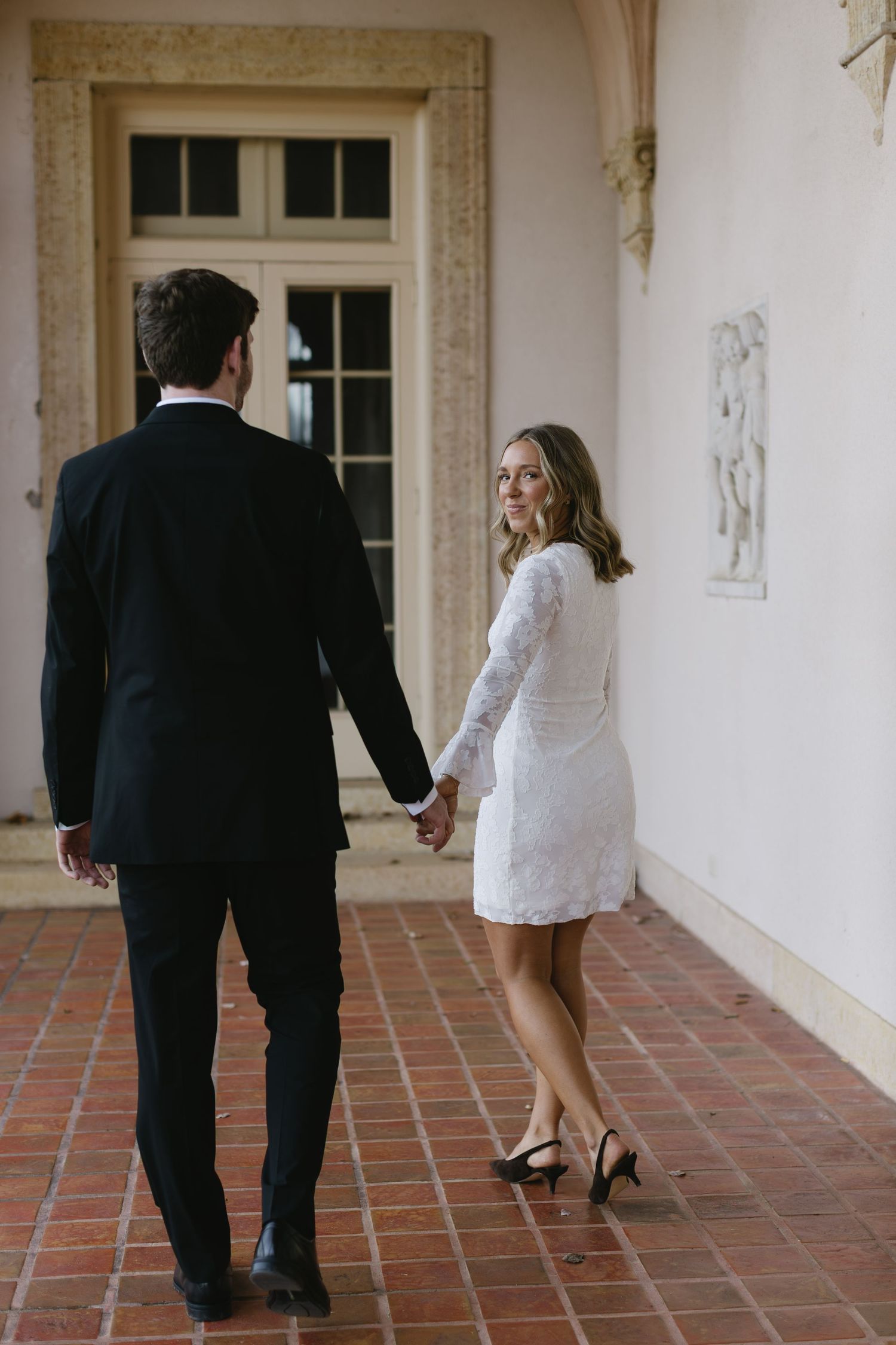 A series of candid wedding shots showing a couple walking and dancing together in a covered walkway.