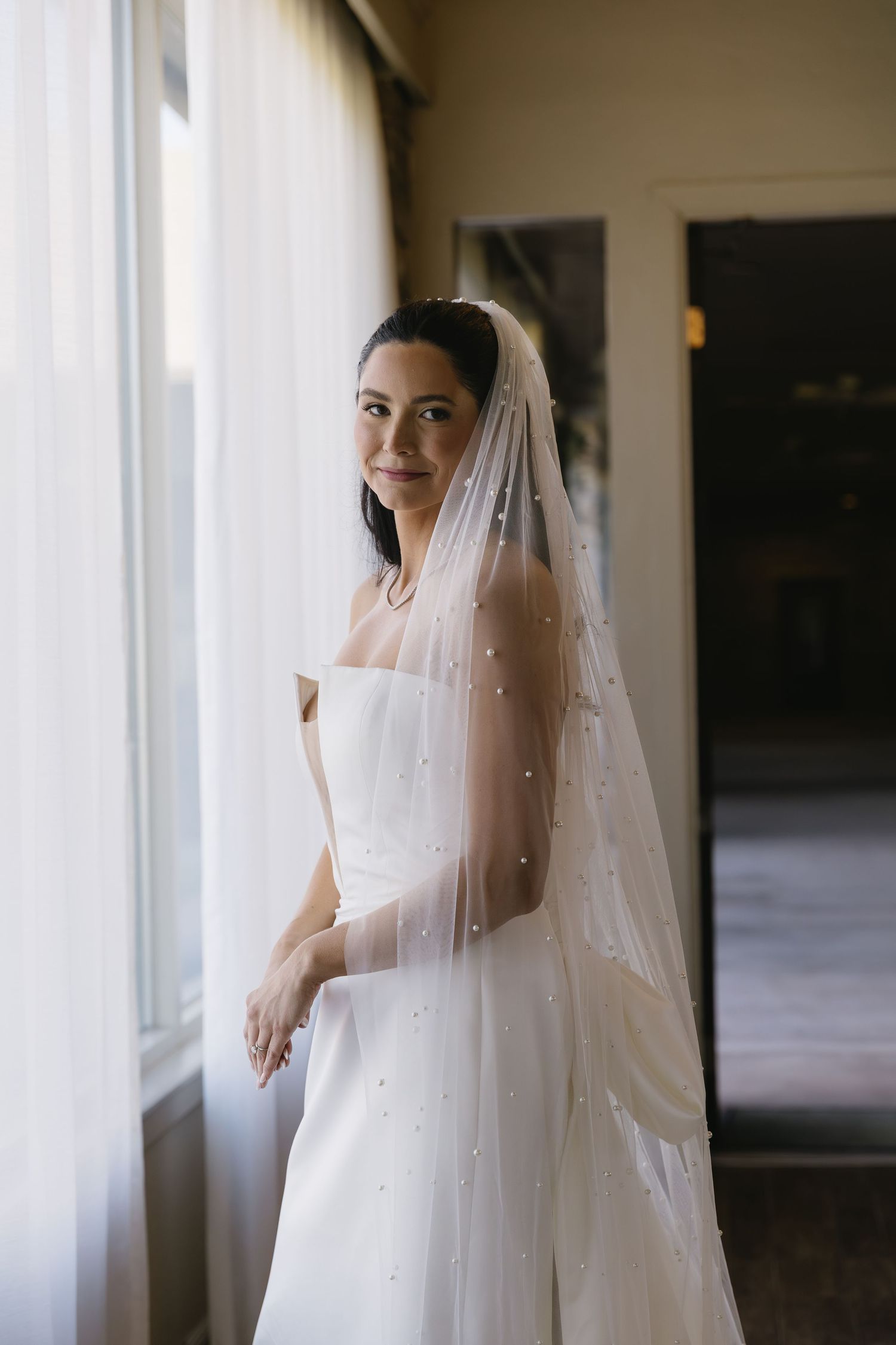 Ethereal bridal portrait with flowing veil and soft natural window light.