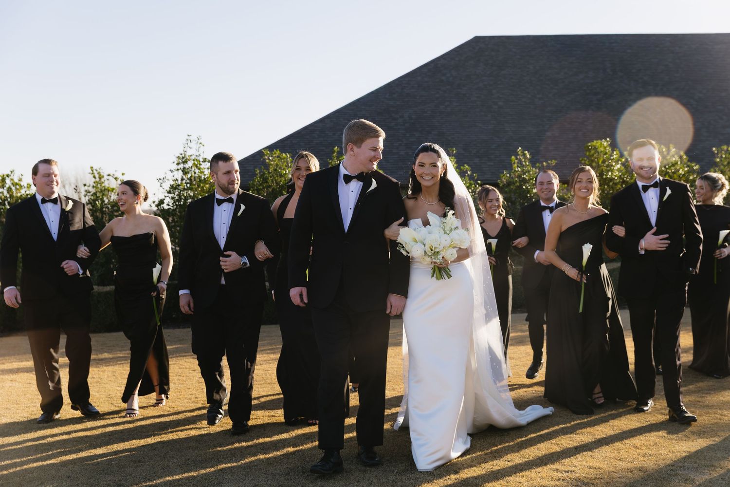 Wedding party members walk together during golden hour outdoor photography session.