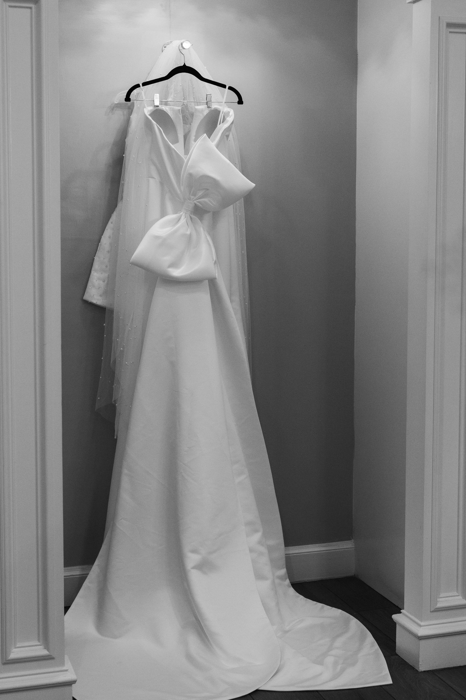 White wedding dress hanging on display in a dressing room with dramatic lighting.