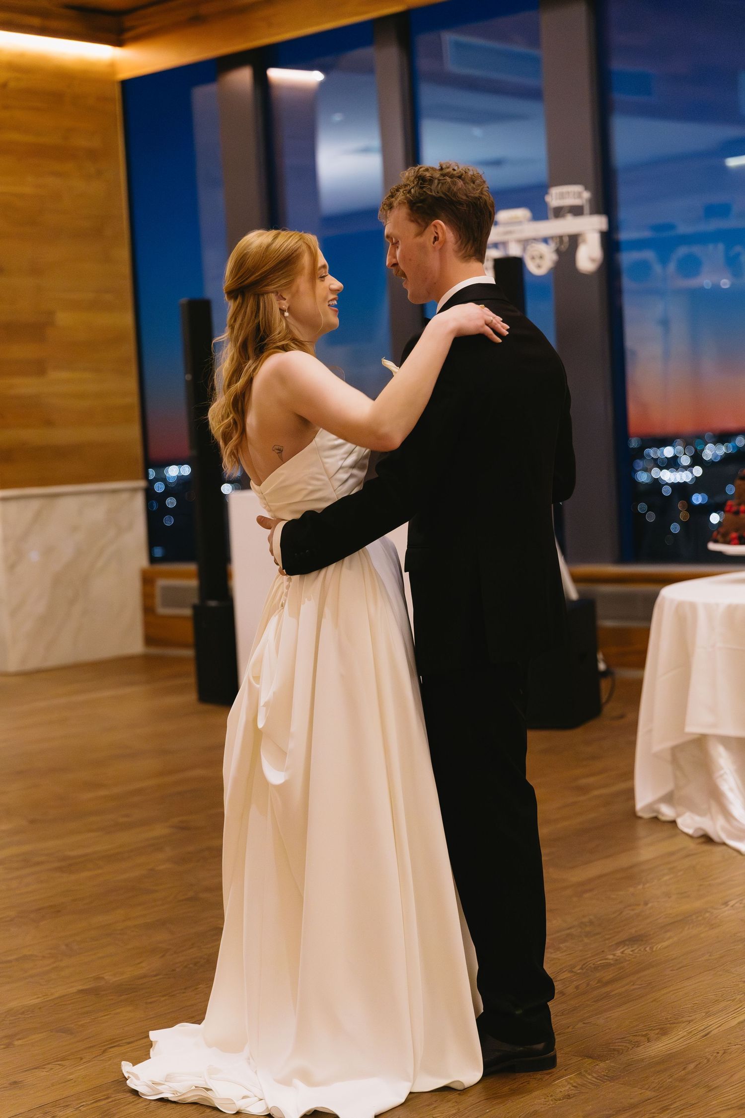 A couple dances together on a wooden floor during their wedding reception.