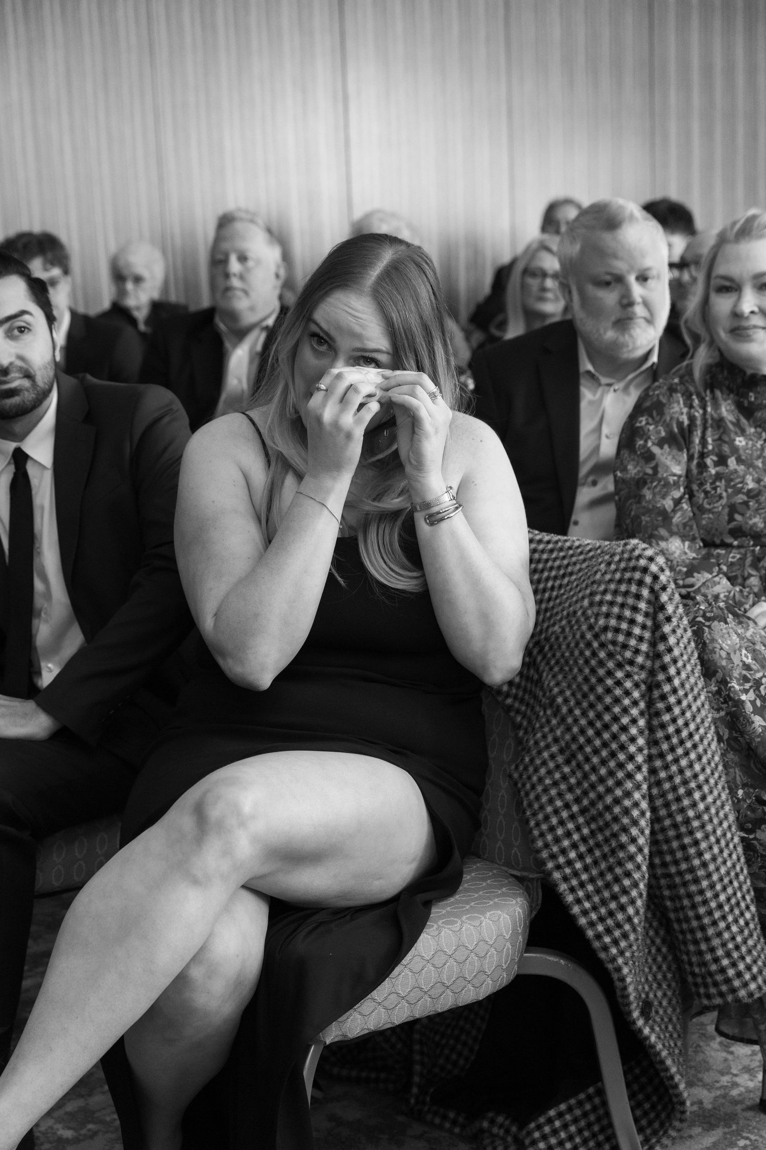 Wedding guests show emotional reactions during ceremony in black and white photography.