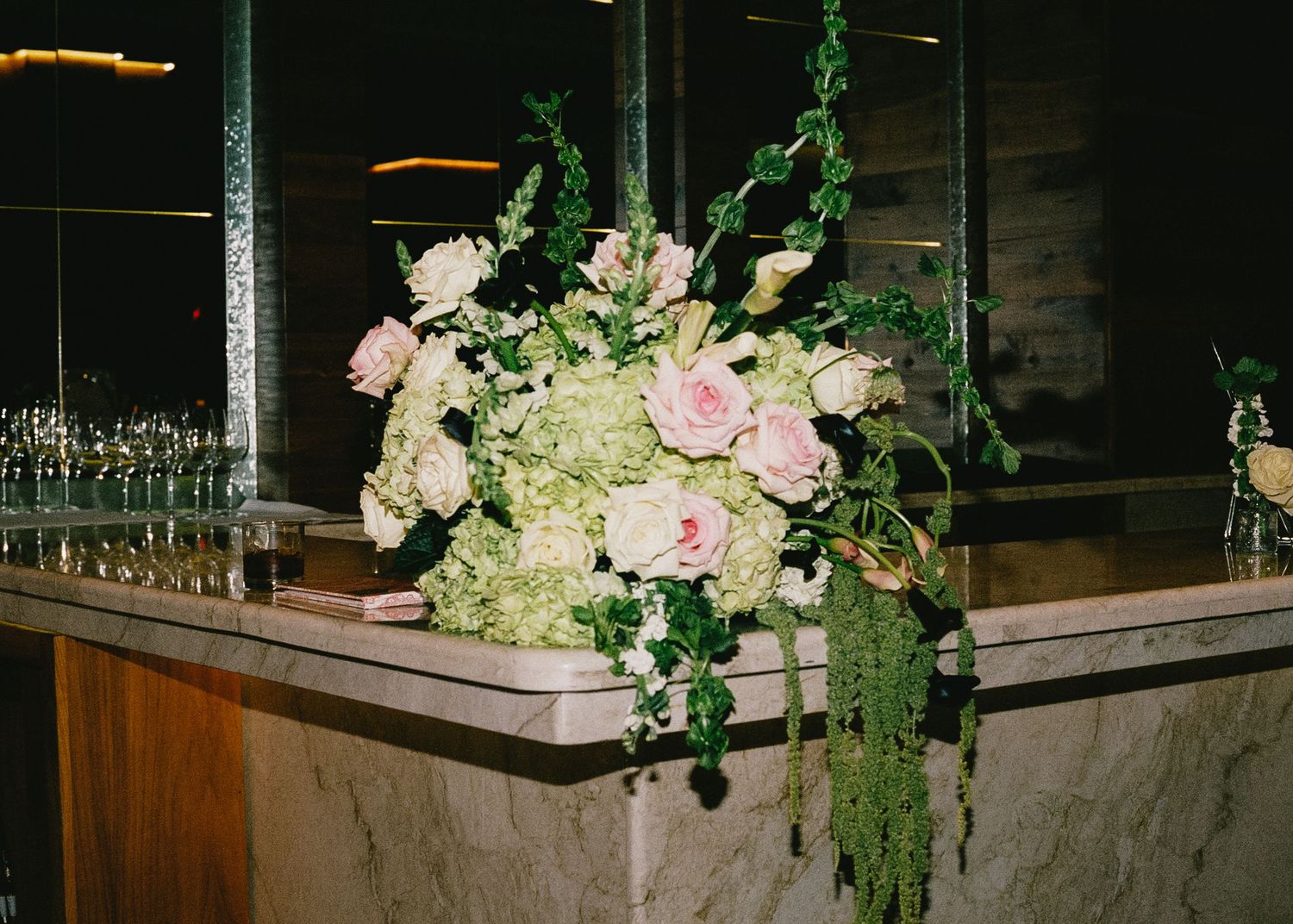 Floral arrangements with pink roses decorating a dark wooden reception venue.