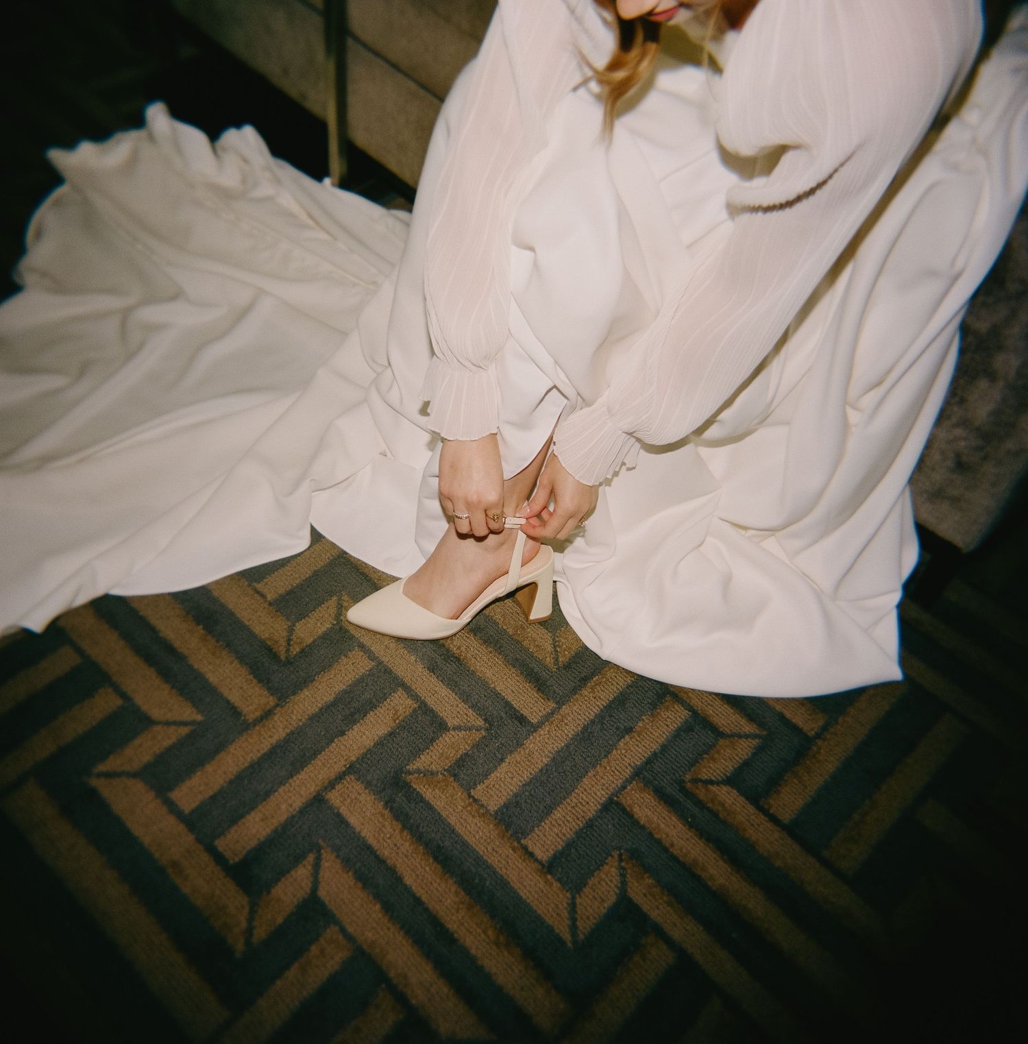 Close-up view of a wedding dress flowing over a patterned floor during a dance.
