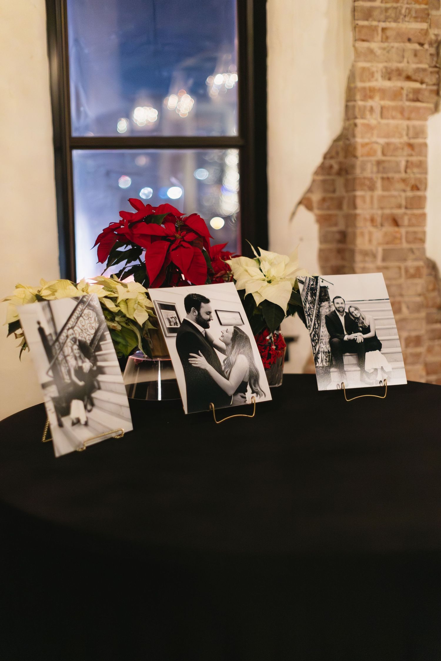 Row of black and white photographs displayed with red and white flowers on dark surface.
