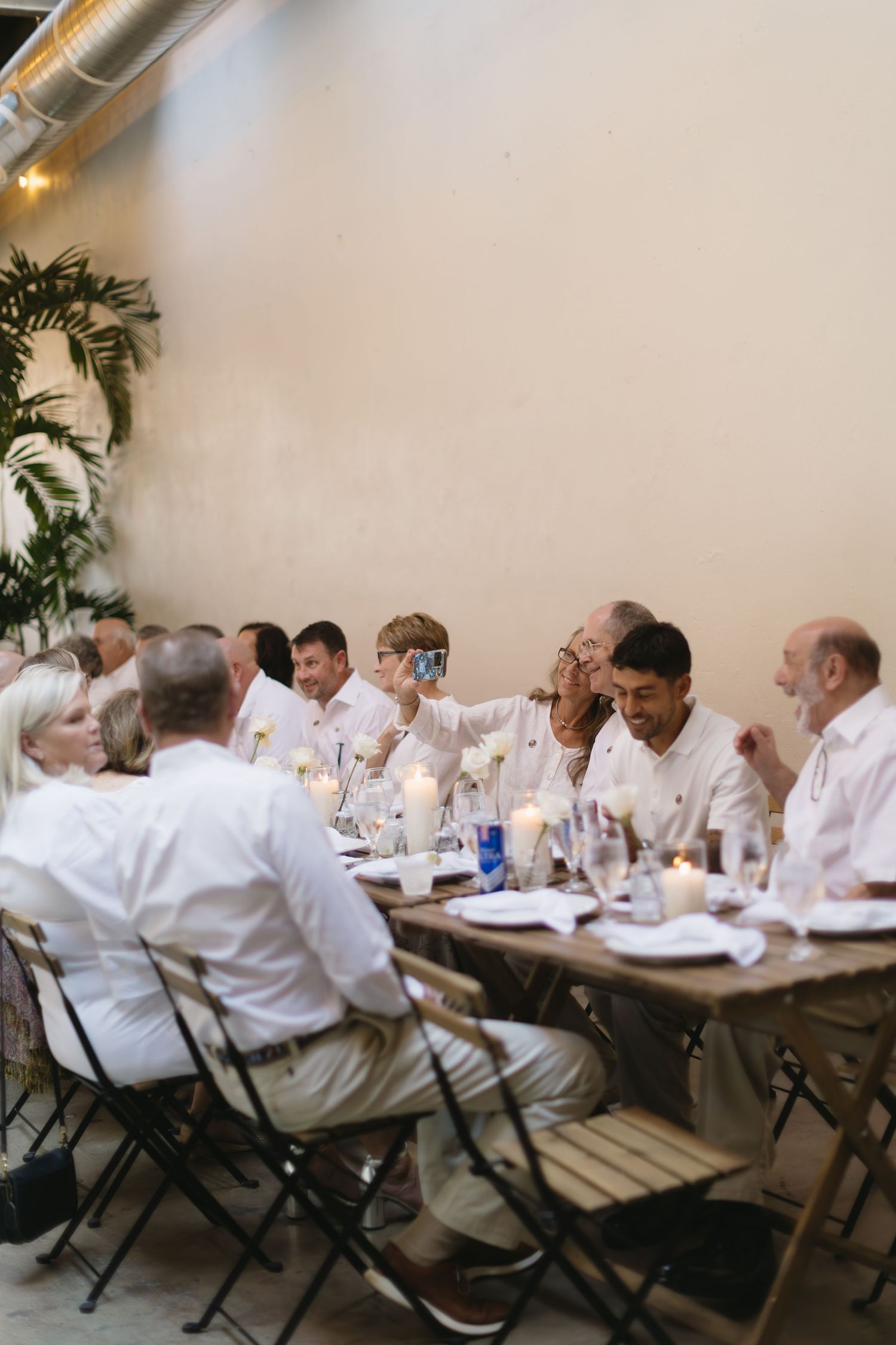 Guests in white attire seated at long tables during a dinner event.