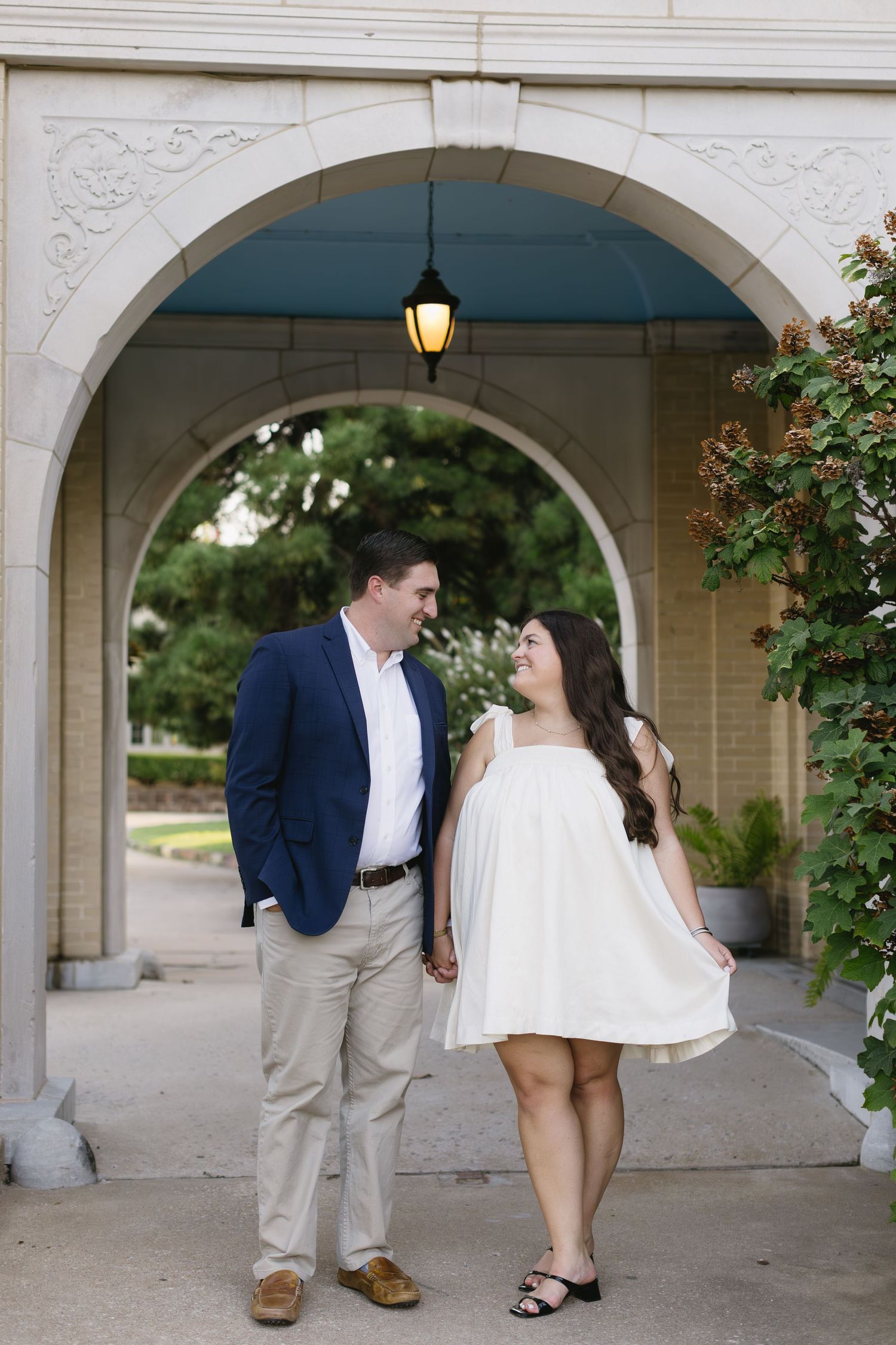 A series of candid engagement photos showing a couple in casual formal wear near stone arches.