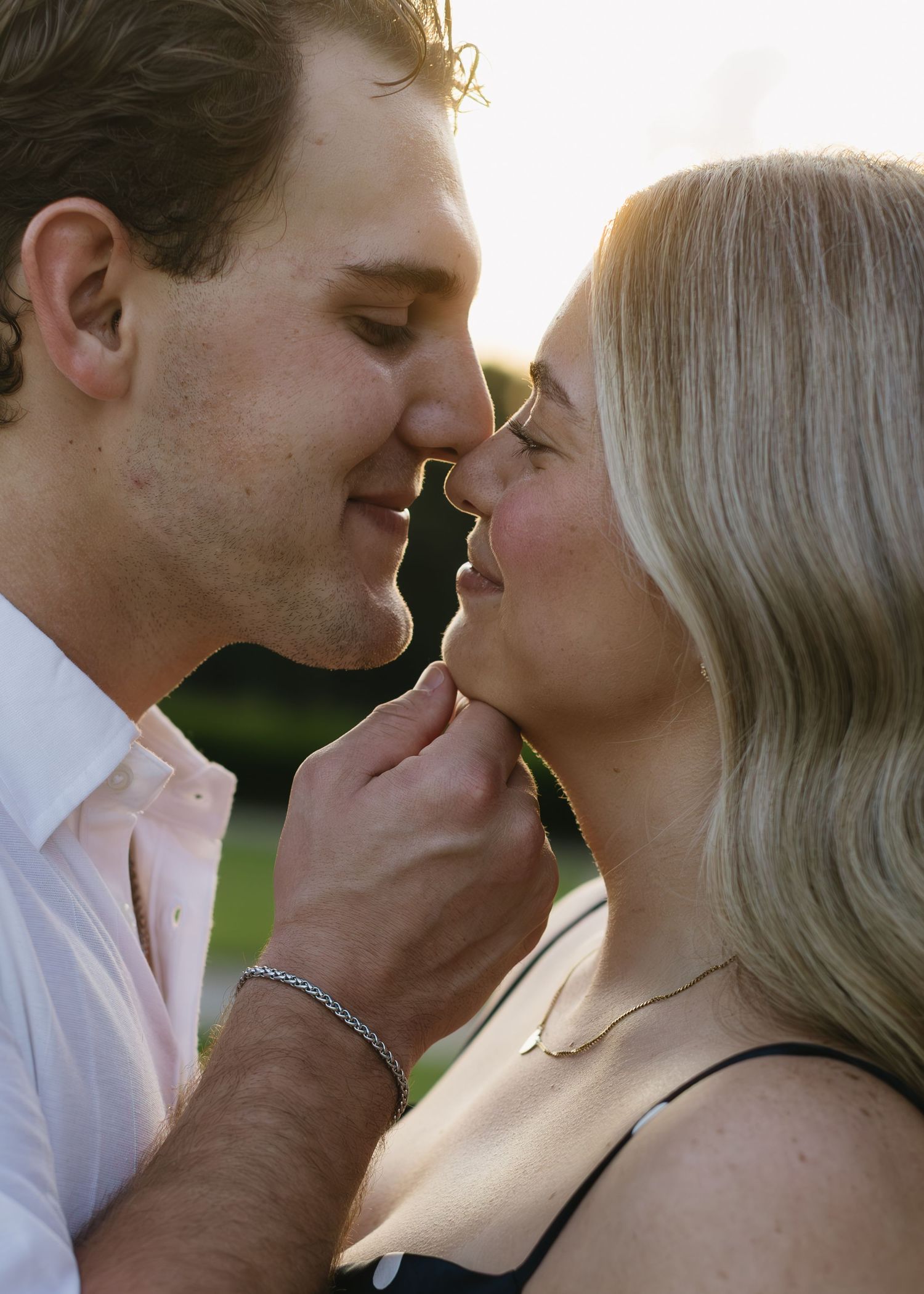 A romantic sunset moment captured between a couple in white shirt and dark dress.