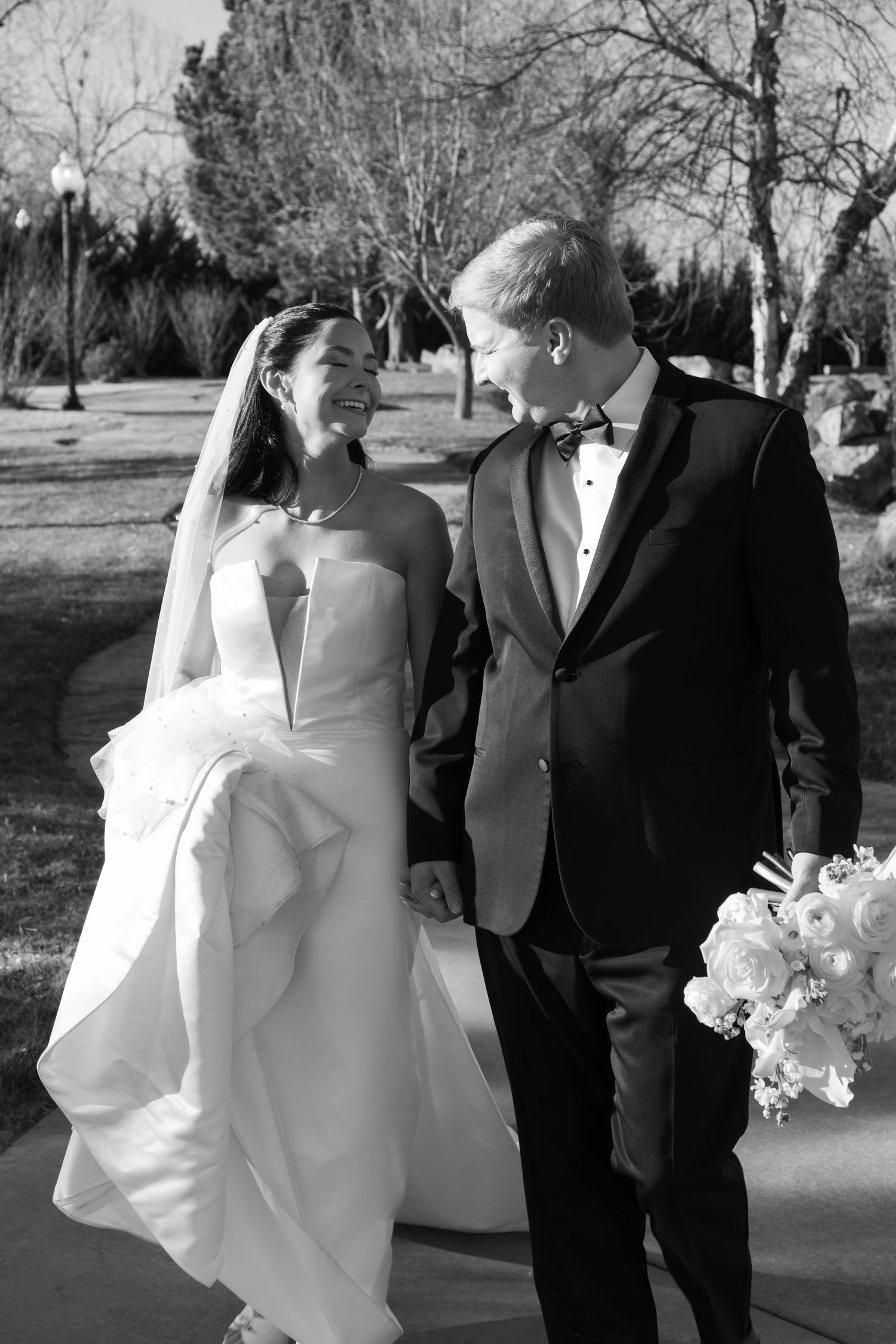 Wedding party poses outdoors in formal attire with winter trees in background.