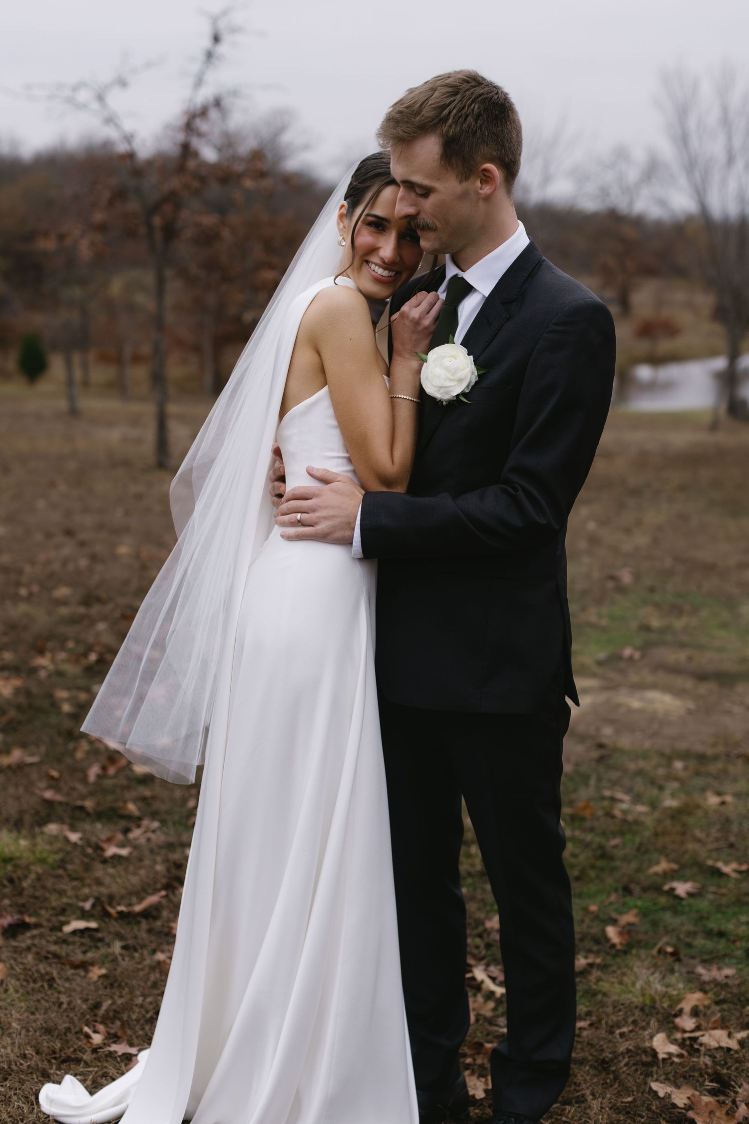 Intimate wedding portrait of couple embracing outdoors in autumn setting.