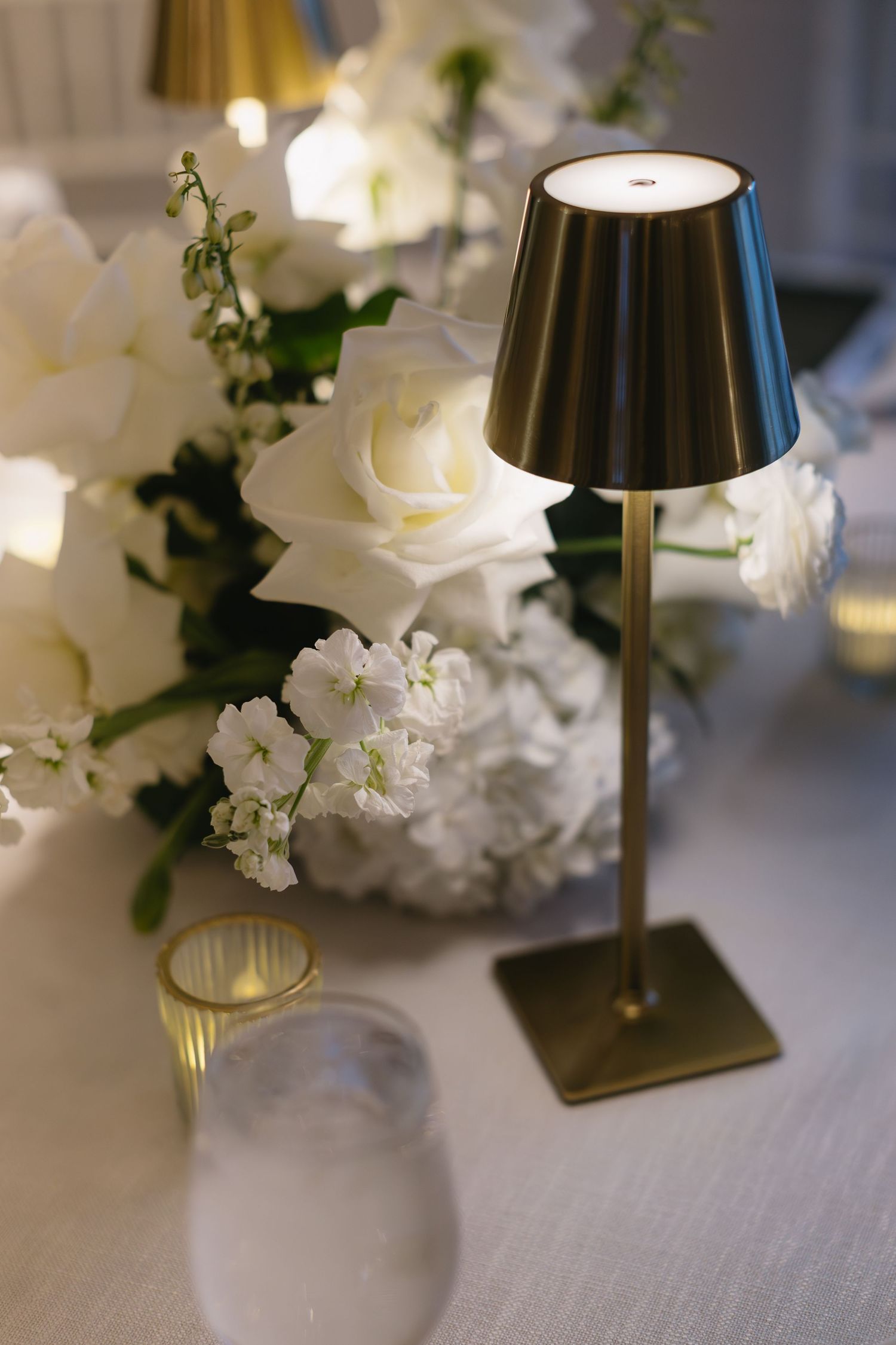 Elegant table decor featuring a black lamp and white roses at a wedding reception.