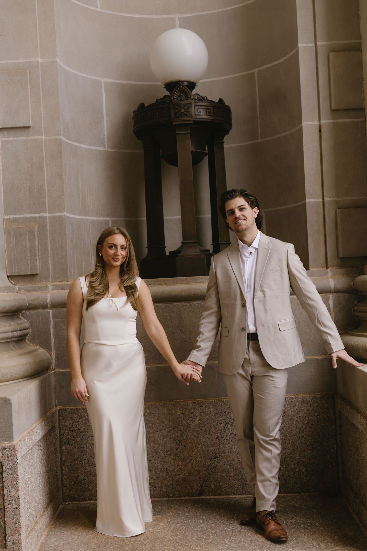 A couple shares intimate moments while posing against an ornate indoor architectural backdrop.