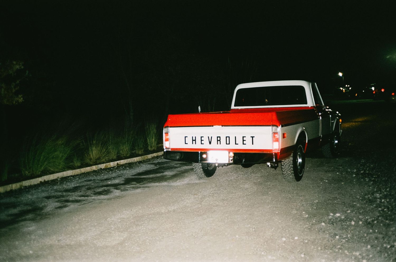 Red Chevrolet pickup truck parked at night with snow on ground.