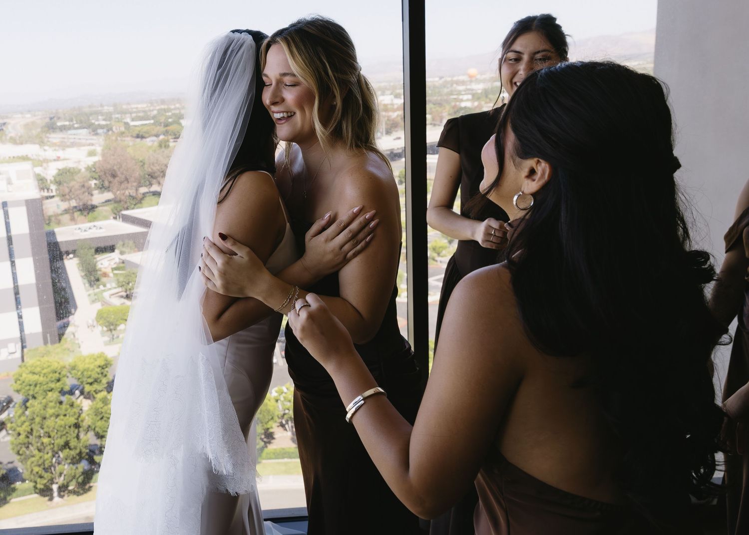 Wedding preparations in a room with large windows and city views.