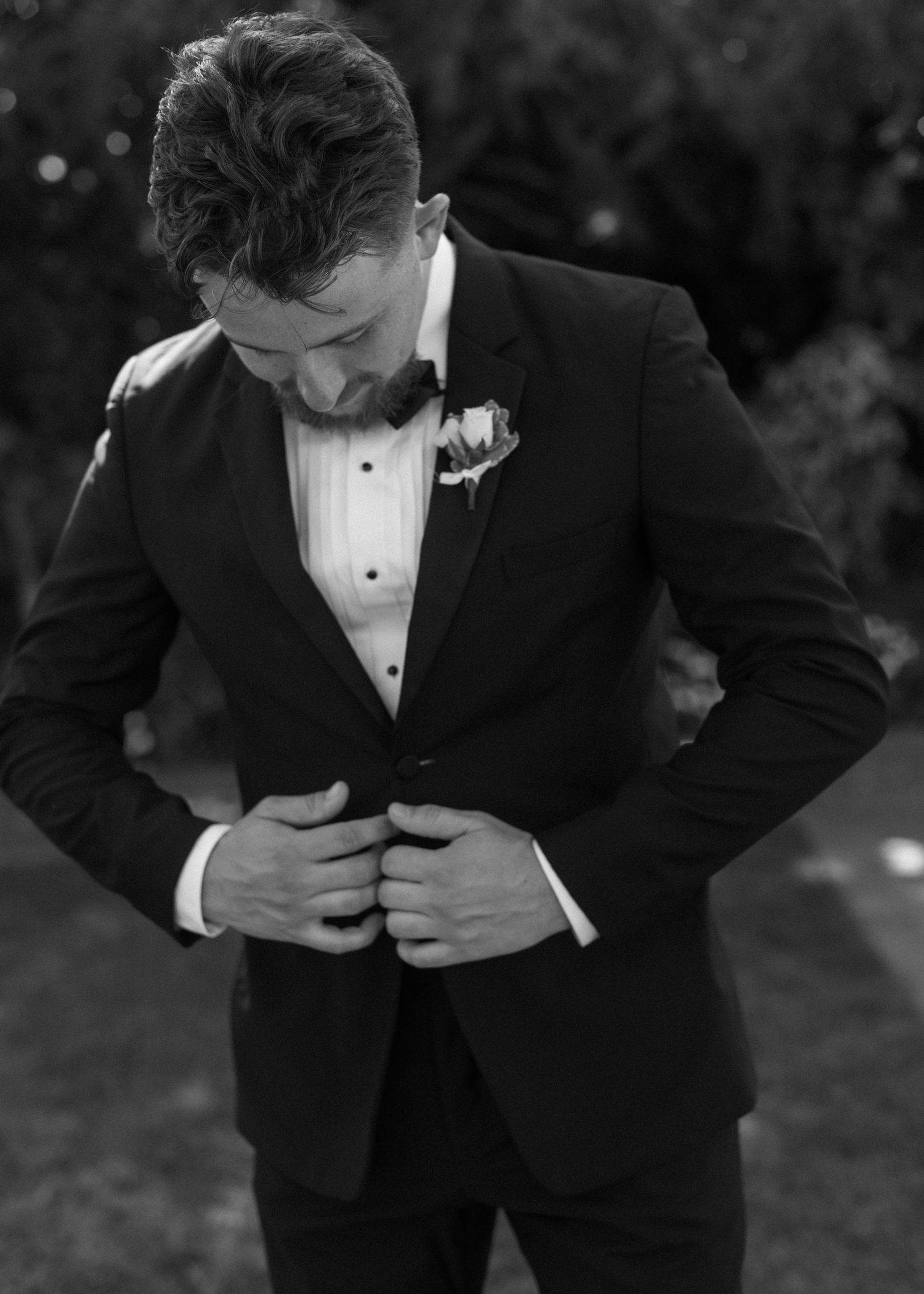 Black and white sequence of a groom adjusting his tuxedo jacket during a wedding photoshoot.