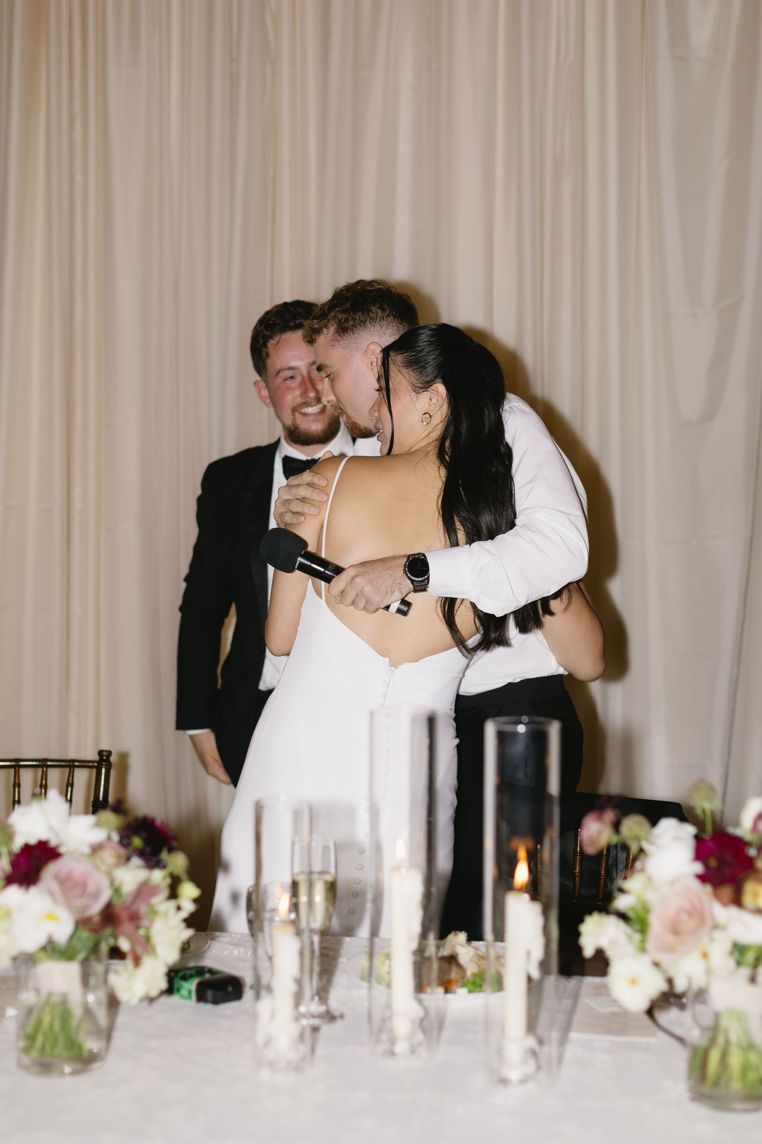 An intimate reception moment captured at an elegant table setting with candles and floral centerpieces.