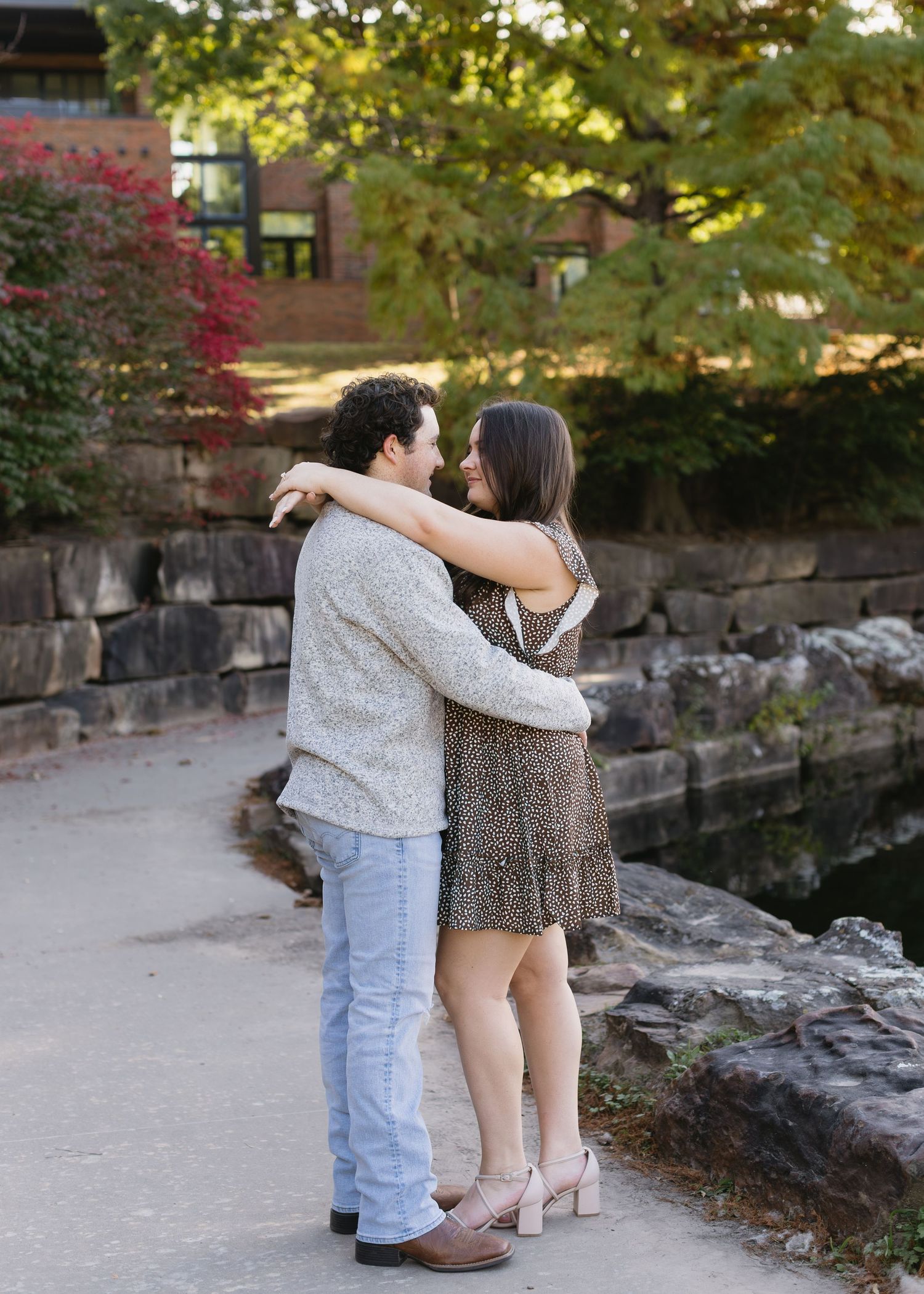 A couple shares a tender moment on stone steps surrounded by autumn foliage.
