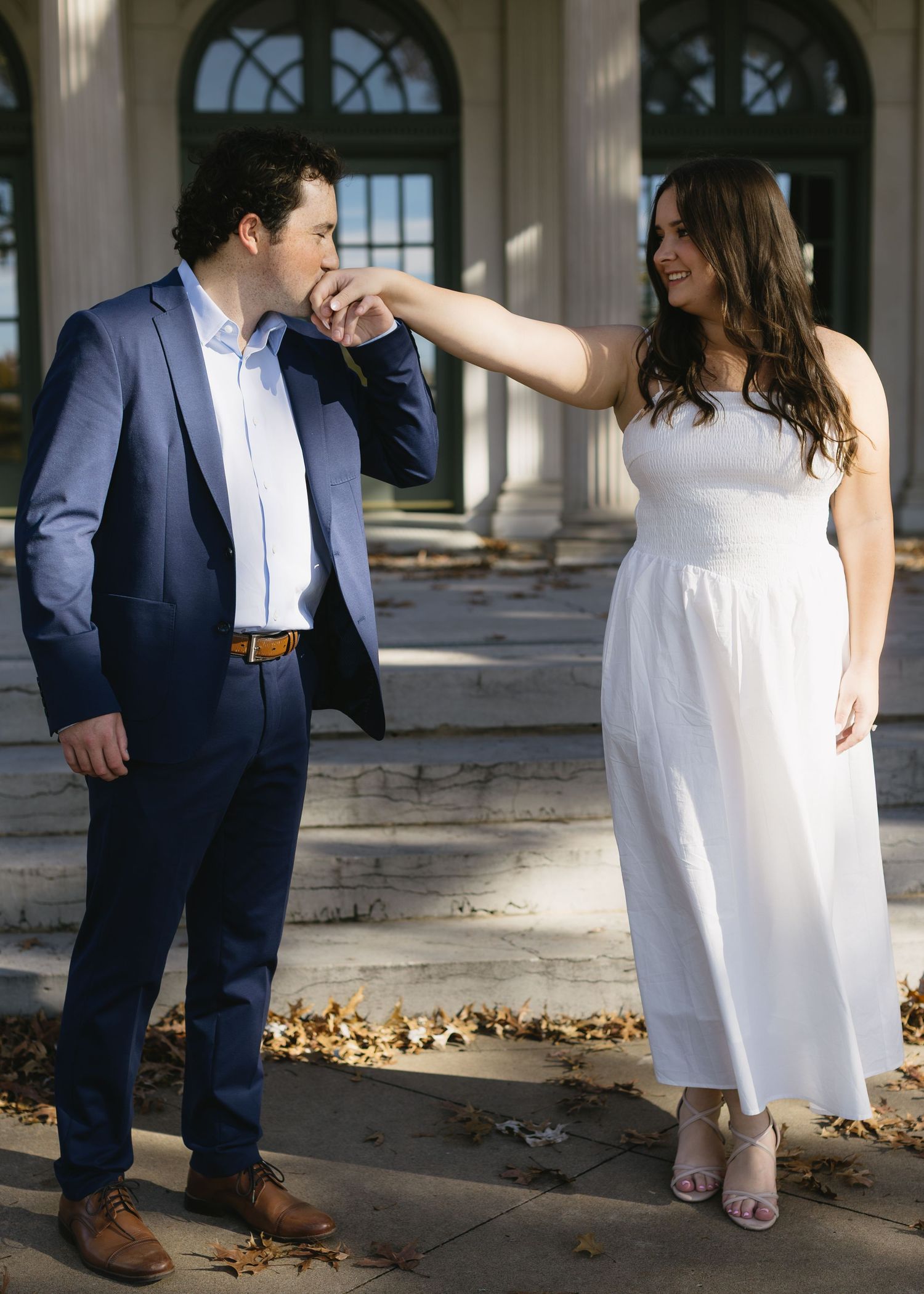 A playful moment between a couple on the steps of a columned building.