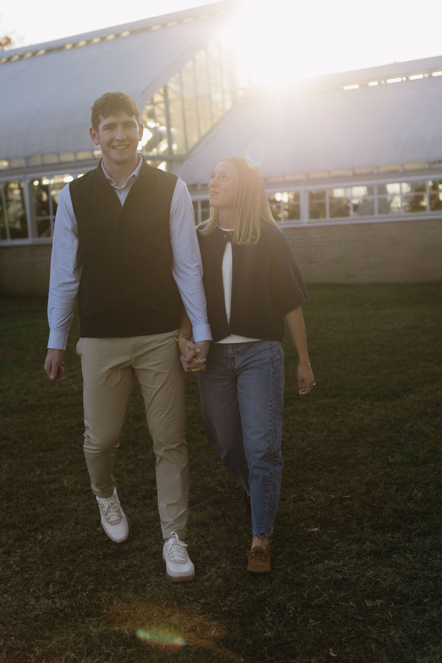 Couple walking together at sunset with lens flare in the background.