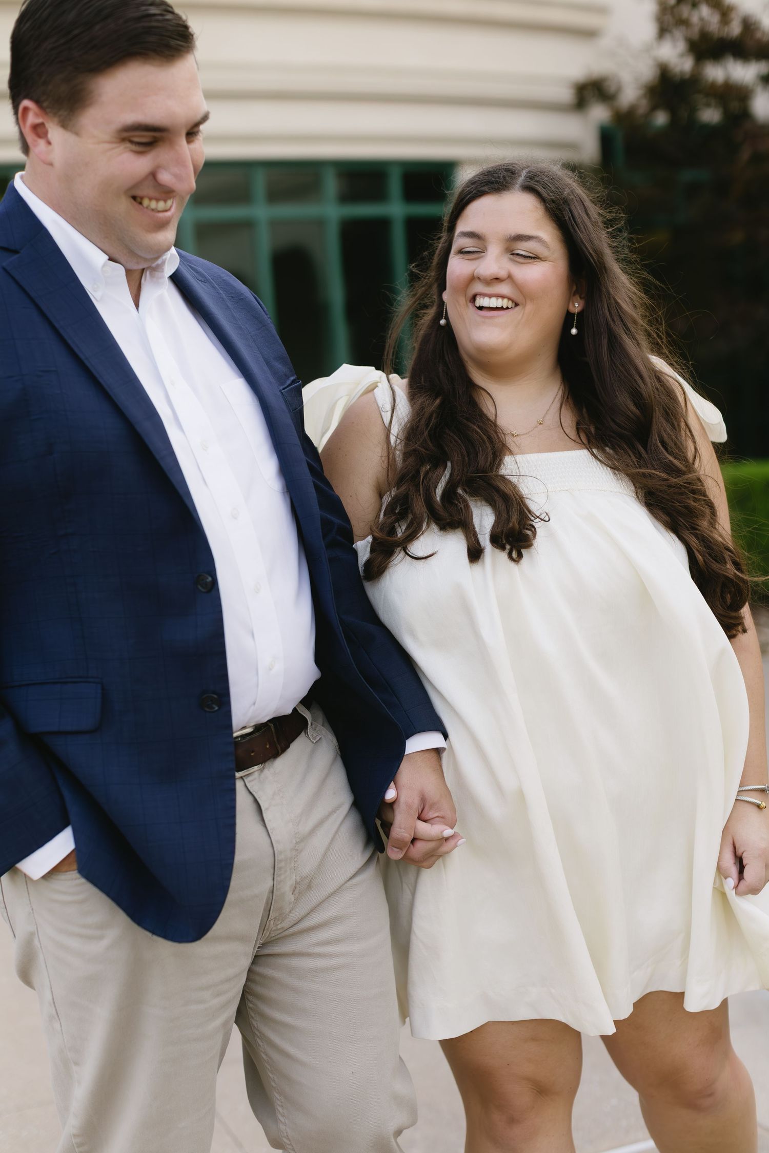 Wedding couple in navy and white attire sharing joyful moments in an outdoor setting.