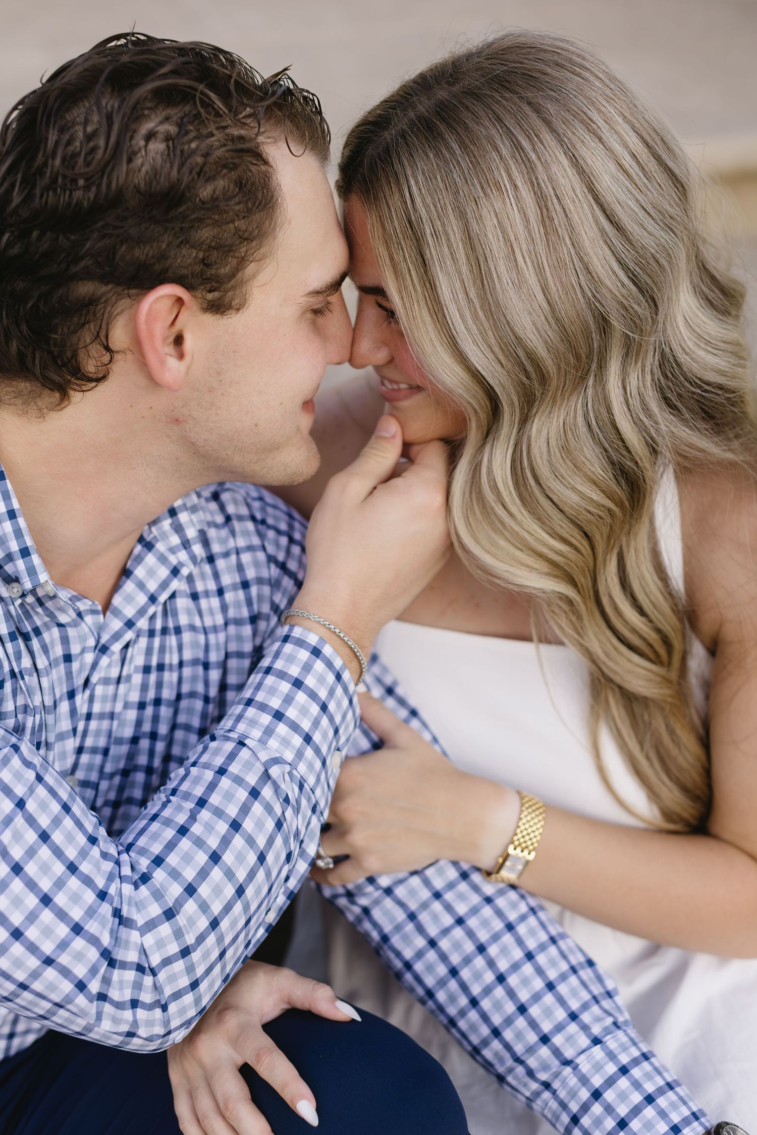 A romantic couple shares an intimate moment with their faces close together, wearing blue checkered and white attire.