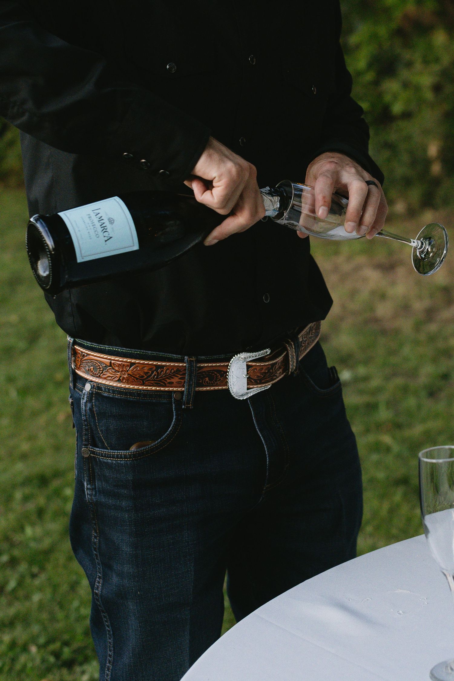 Detail shot of person wearing jeans and leather belt at casual outdoor event.
